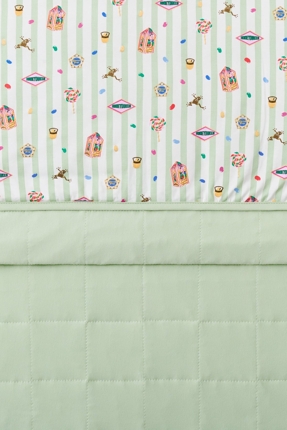 Baby blanket with colorful Harry Potter patterns print on a green and white striped fabric with light green fabric at the back.