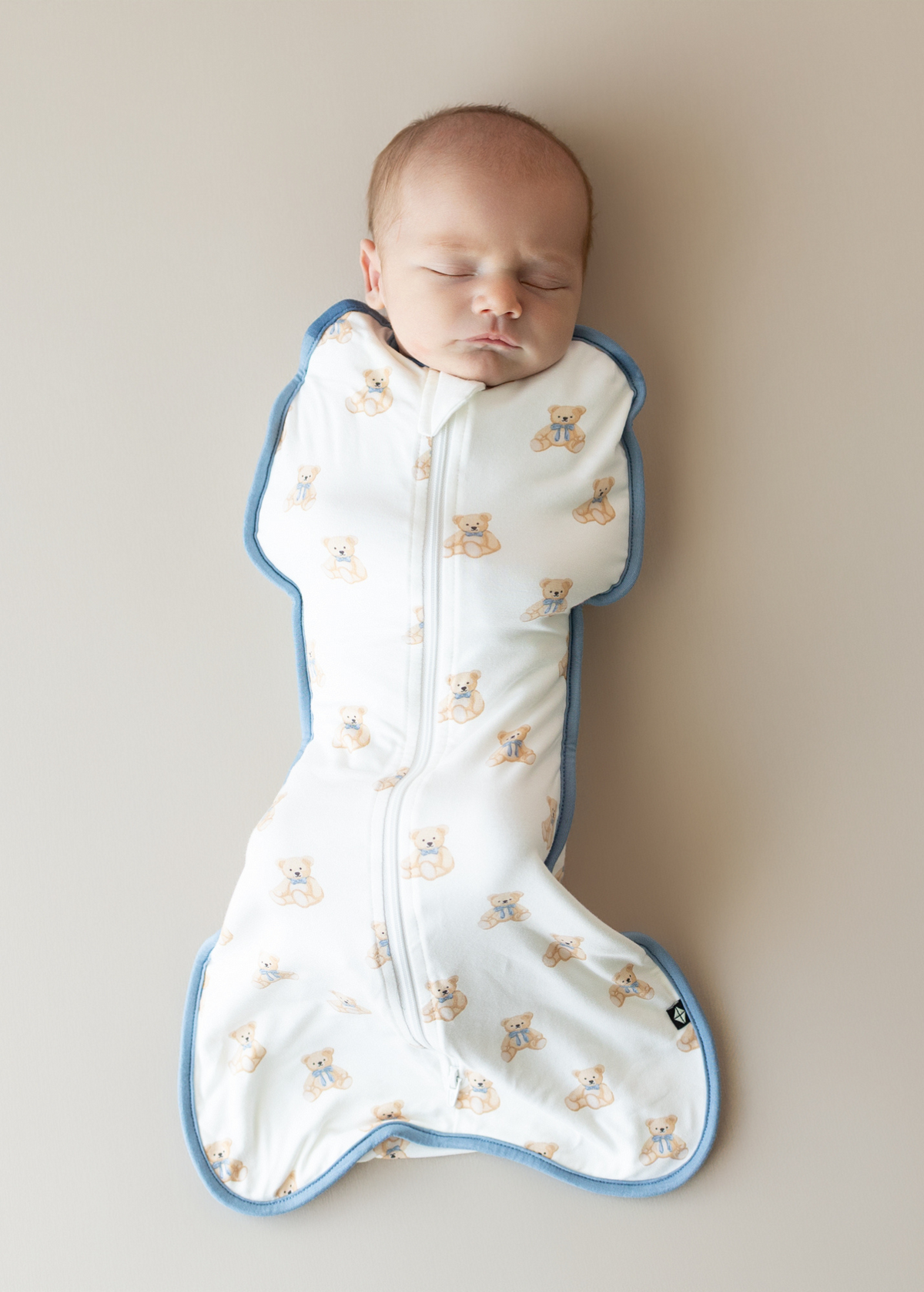 Sleeping baby wearing bear-print swaddle bag