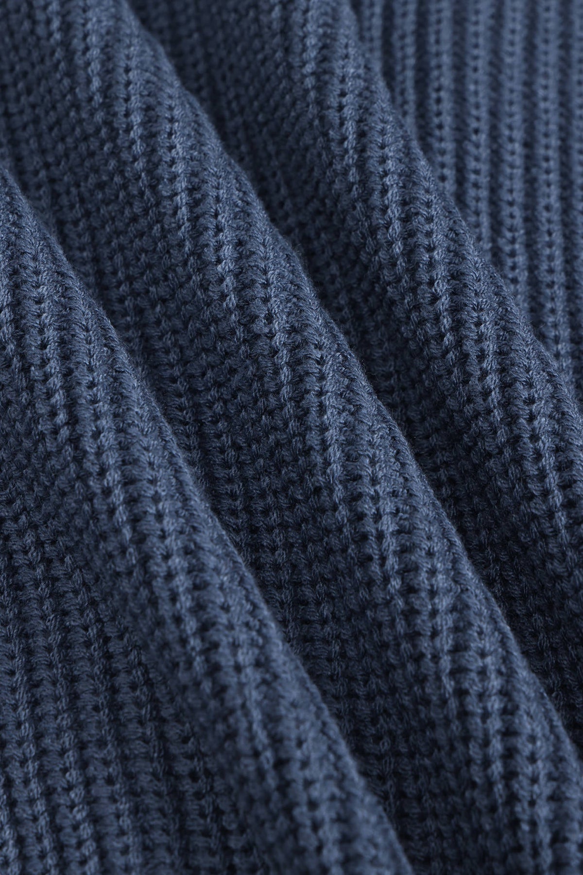 Close-up of a dark navy blue ribbed knit fabric texture with soft diagonal folds.