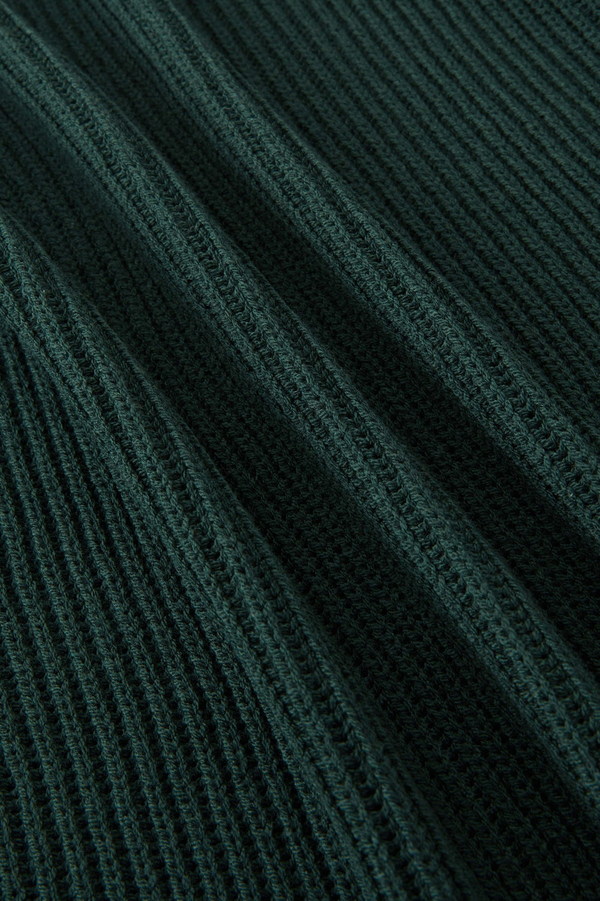 Close-up of a dark forest green ribbed knit fabric with a textured vertical stripe pattern.