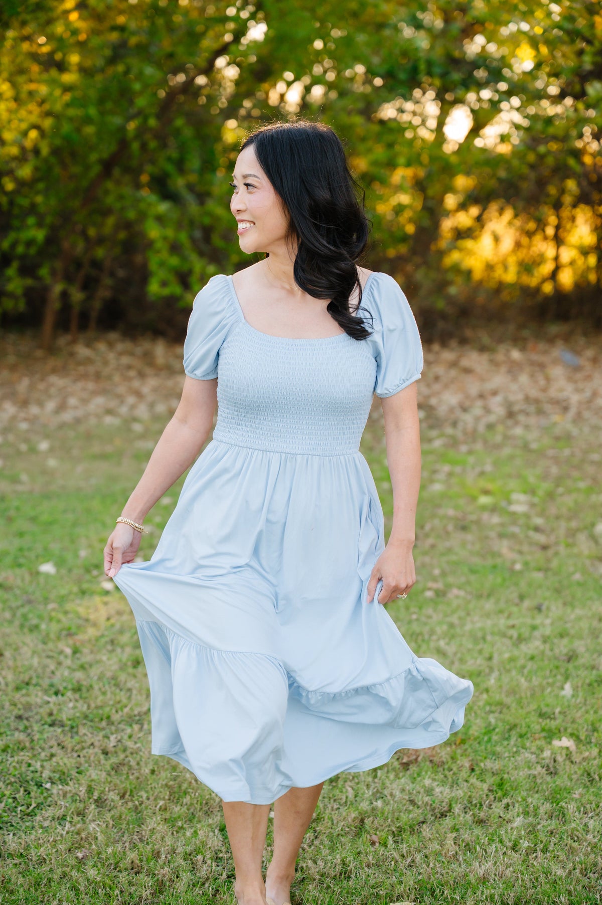 Female walking in a grassy field modeling the soft and breathable Women’s Smocked Dress in Breeze