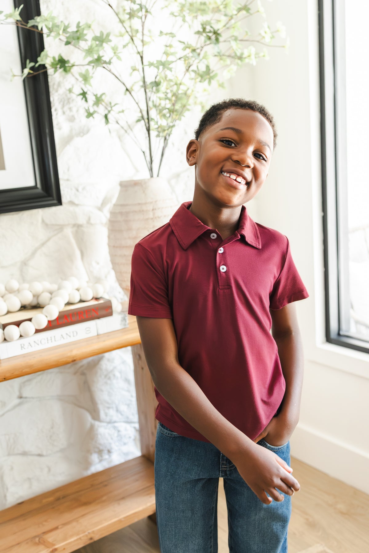 Boy smiling in Toddler Short Sleeve Polo in Burgundy on blue jeans