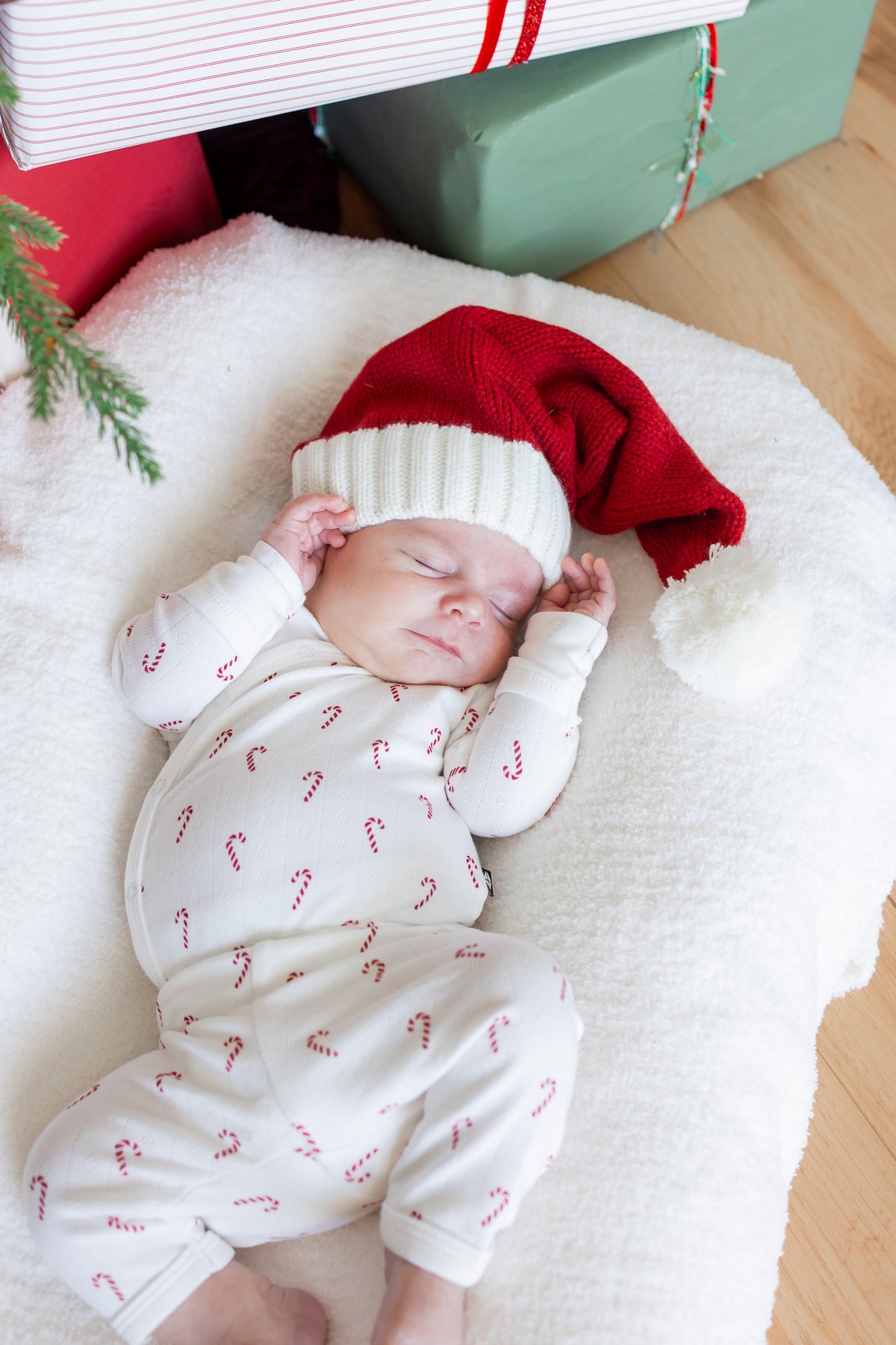 Baby sleeping wearing Pointelle Kimono Set in Candy Cane and red hat on a white sheet