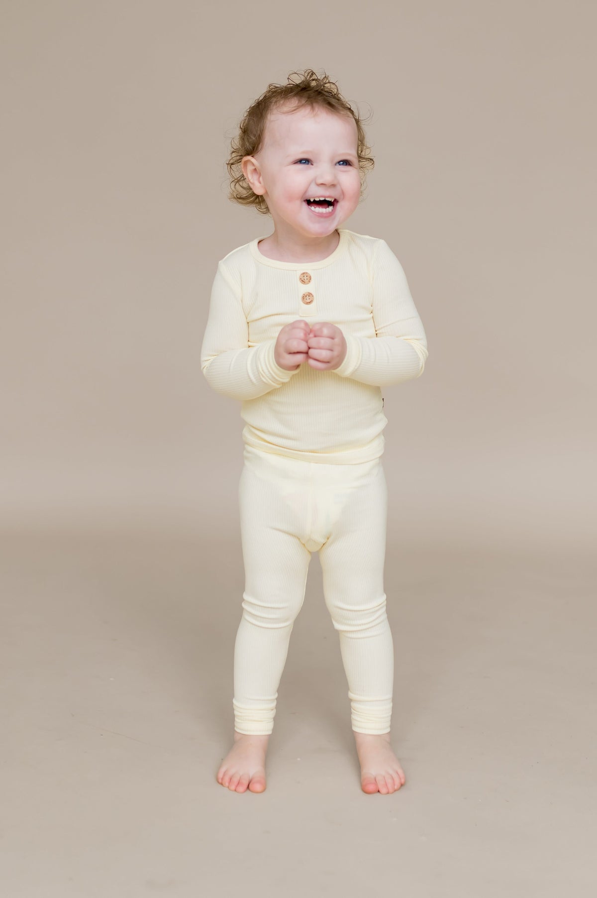 Smiling child standing wearing the Ribbed Henley Set in Chamomile