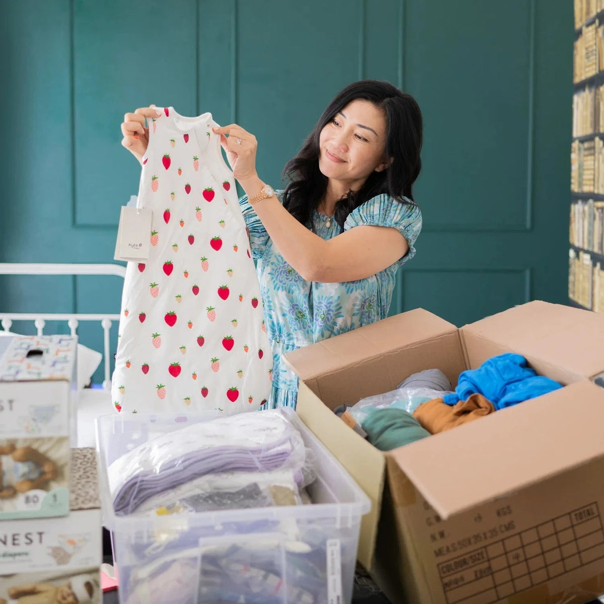 Kyte Baby owner, Ying, holding a sleep bag surrounded by boxes