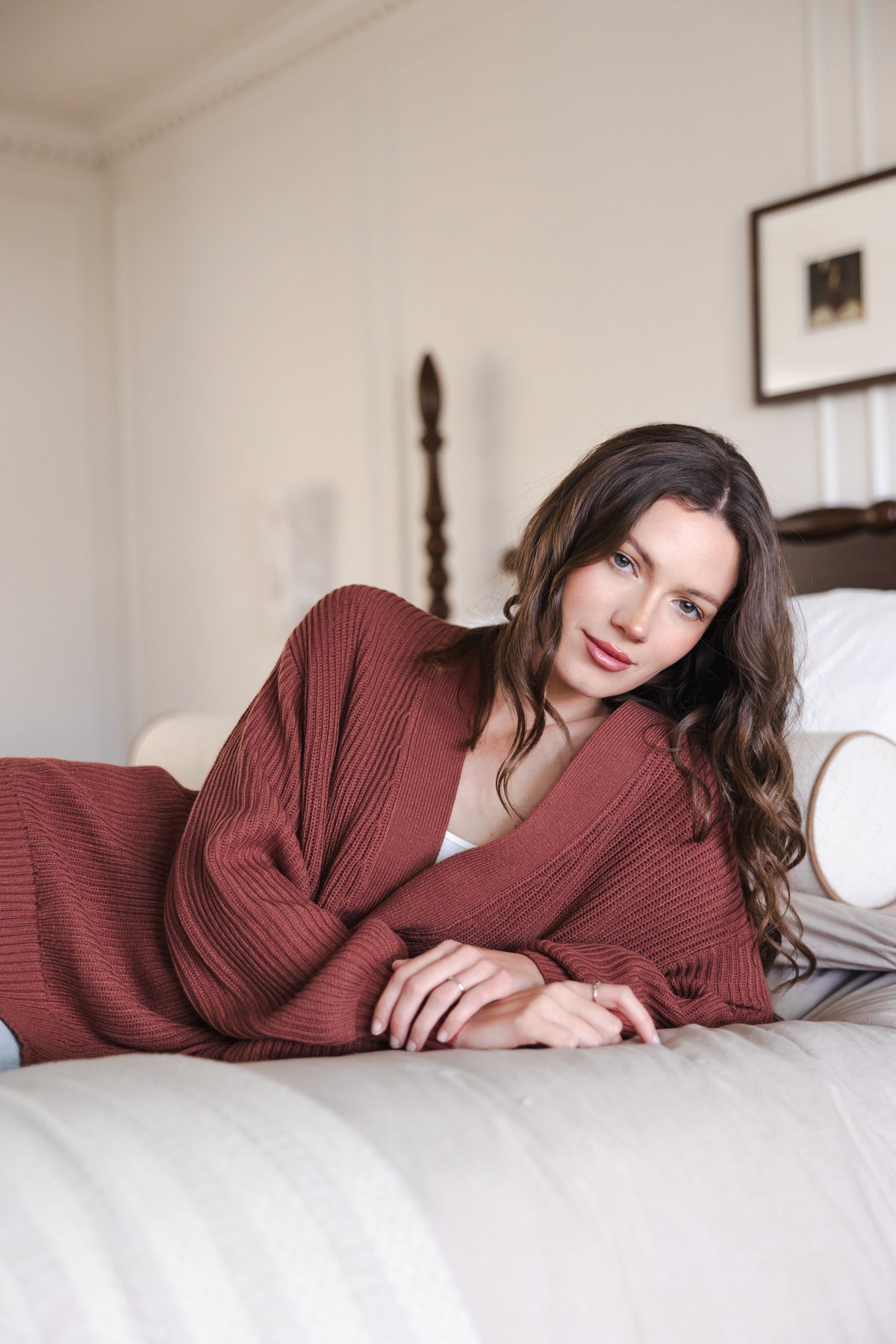 Modal lying on bed wearing Chunky knit oversized cardigan in ember over white t-shirt