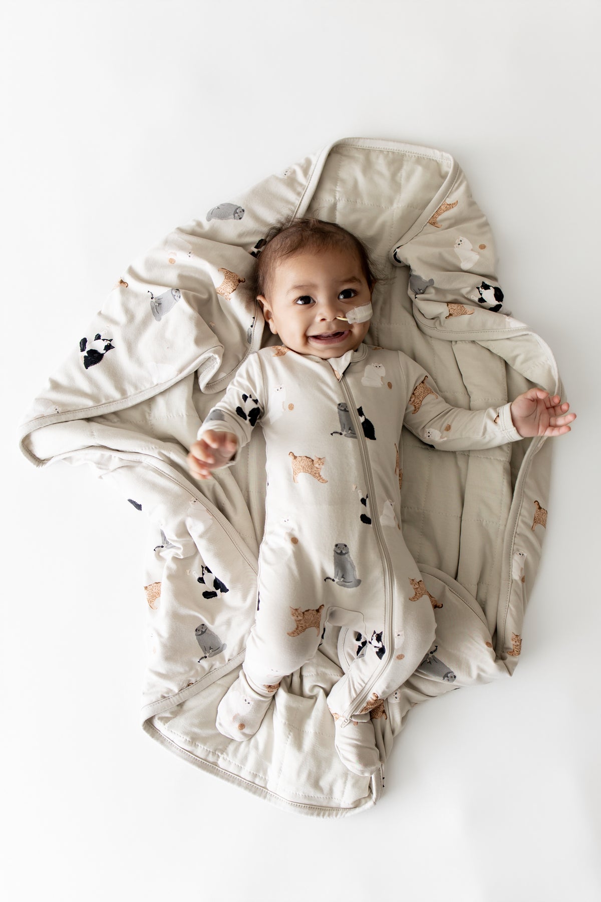 Smiling infant laying on a Baby Blanket in Fluffy Cat wearing a matching zippered footie