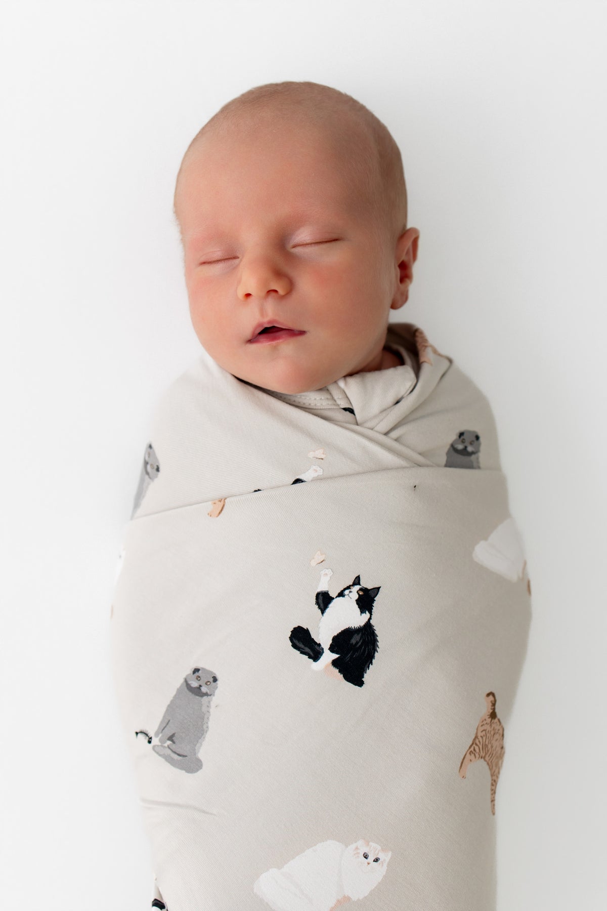 Close up of sleeping newborn wearing the Swaddle Blanket in Fluffy Cat