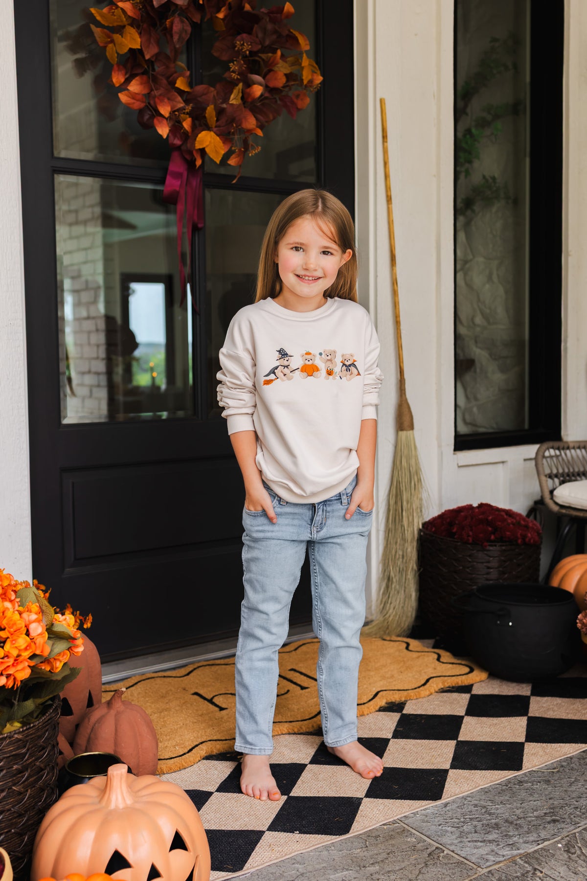 Girl standing outdoors wearing Beige Sweatshirt with Halloween Teddy print in its center