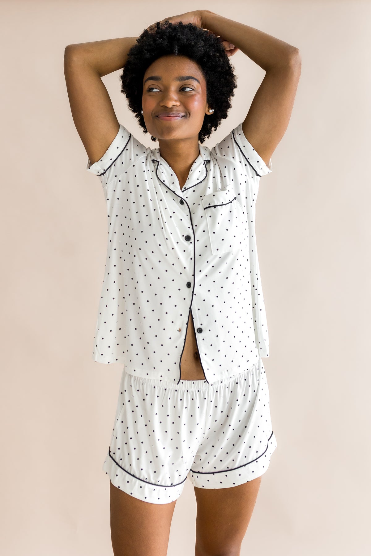 Model smiling in Women's short sleeve pajama set with Midnight Polka Dot print on a beige background