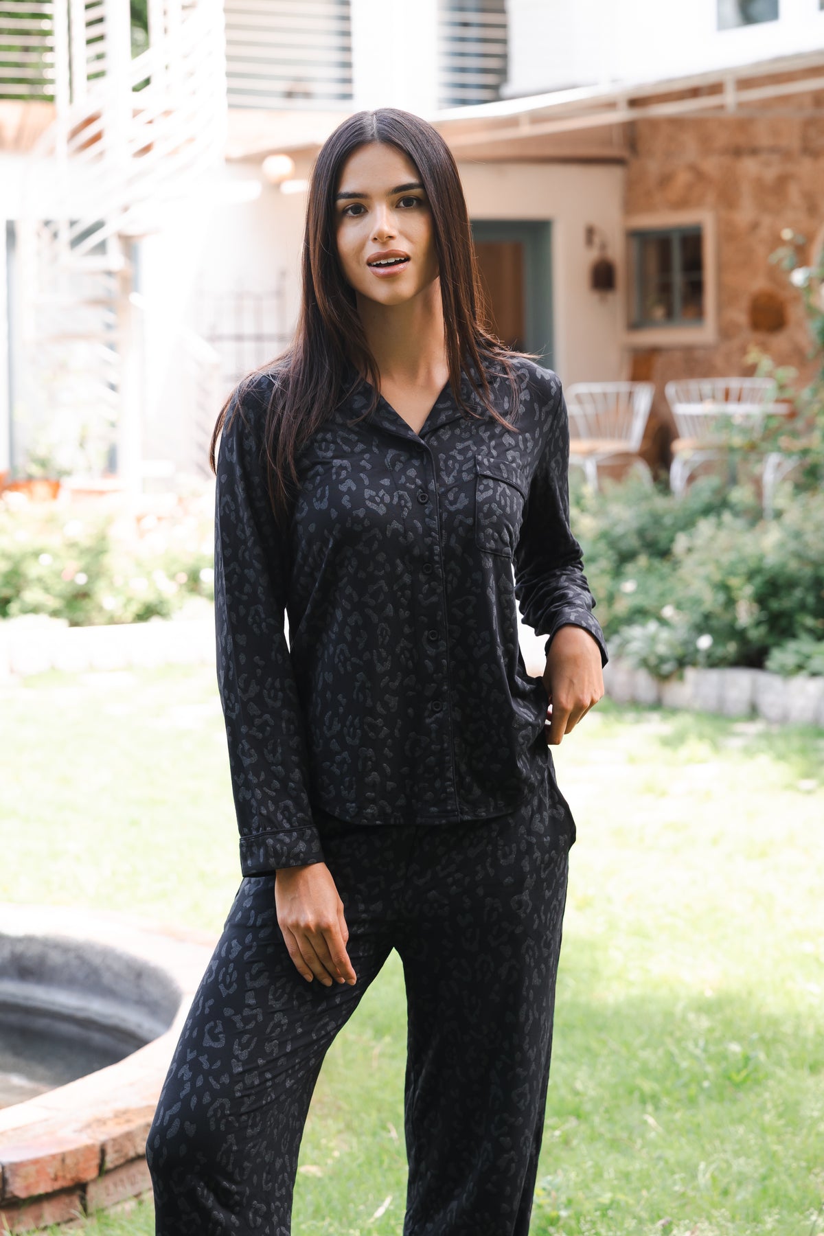 Female standing outside in front of a house wearing the Long-Sleeved Women's Pajama Set in Midnight Leopard