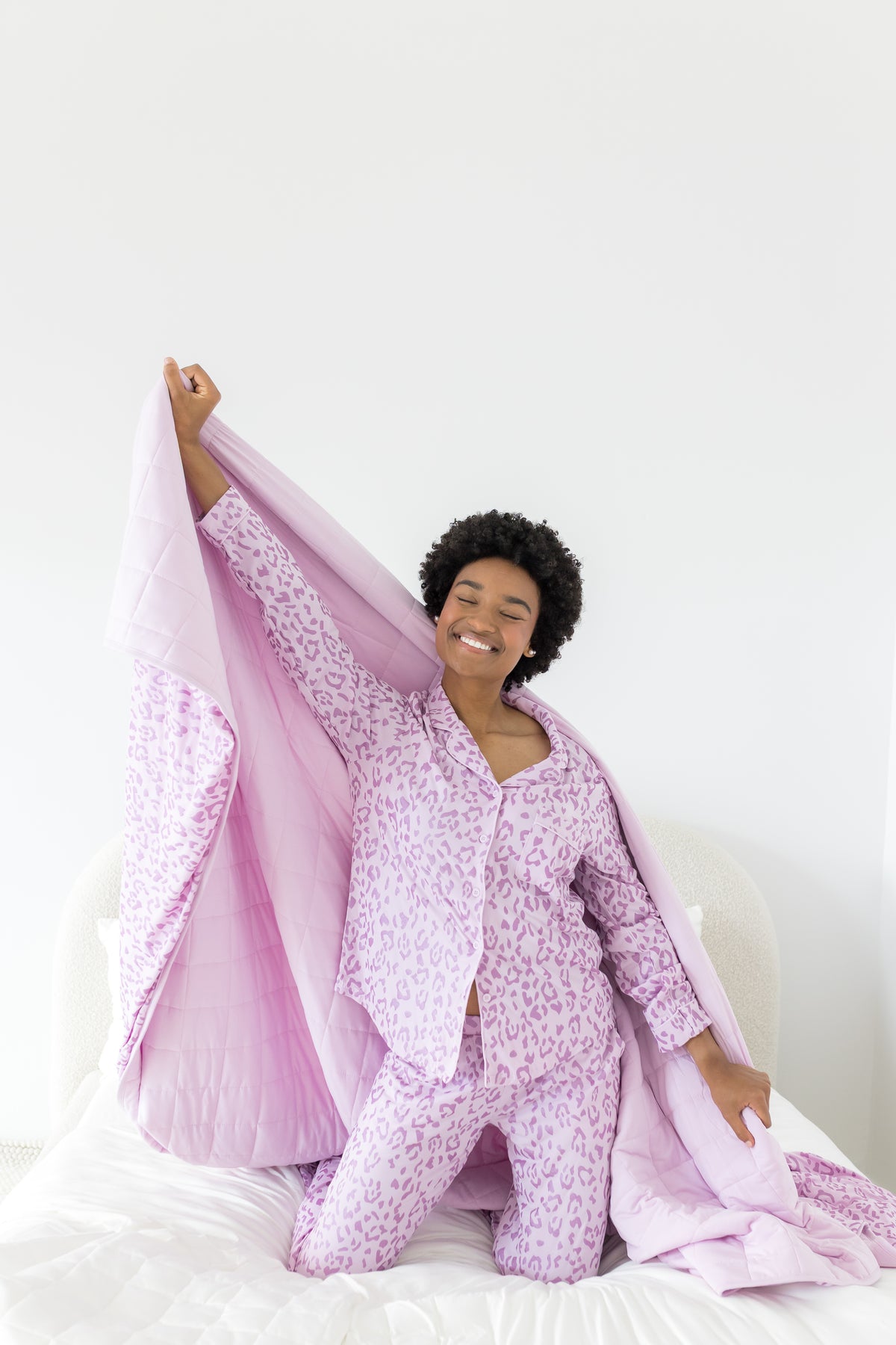 Model posing with Adult Blanket in Thistle Leopard print wearing similar print long sleeve pajamas on a white background