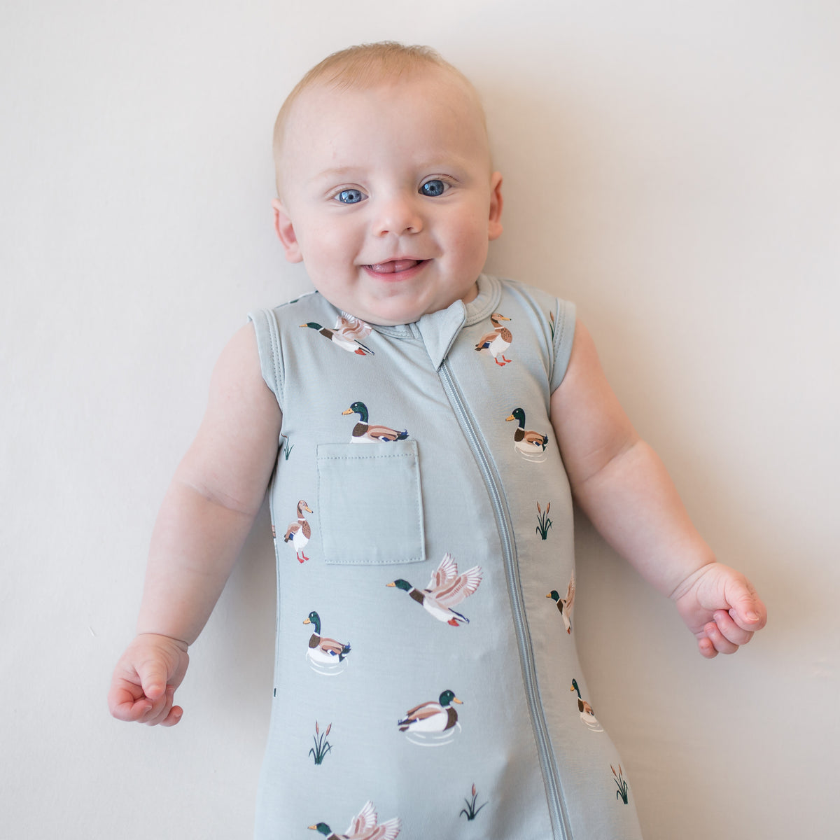 Close up of an infant wearing the Zippered Sleeveless Romper in Mallard Duck