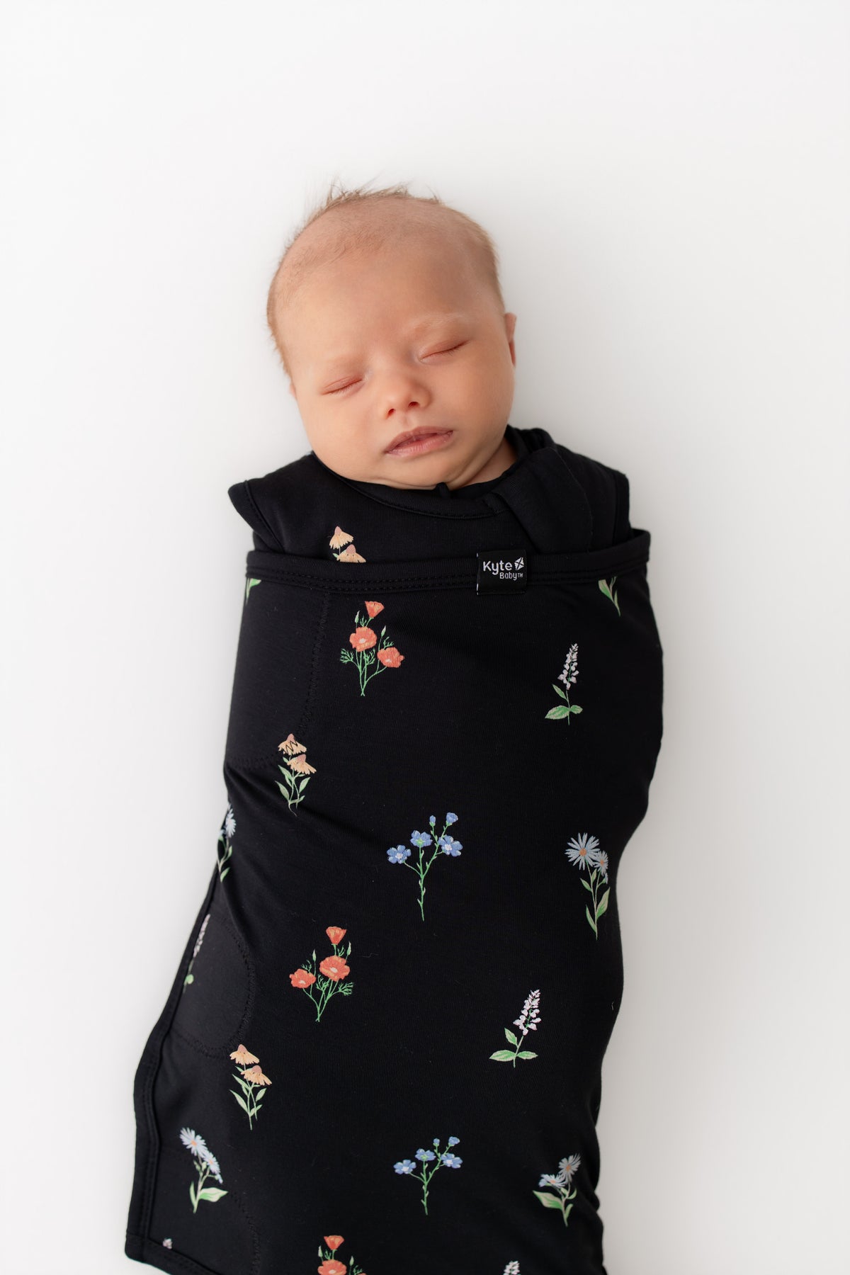 Baby in Sleep Bag Swaddler in Midnight Wildflower 1.0 print on a white background
