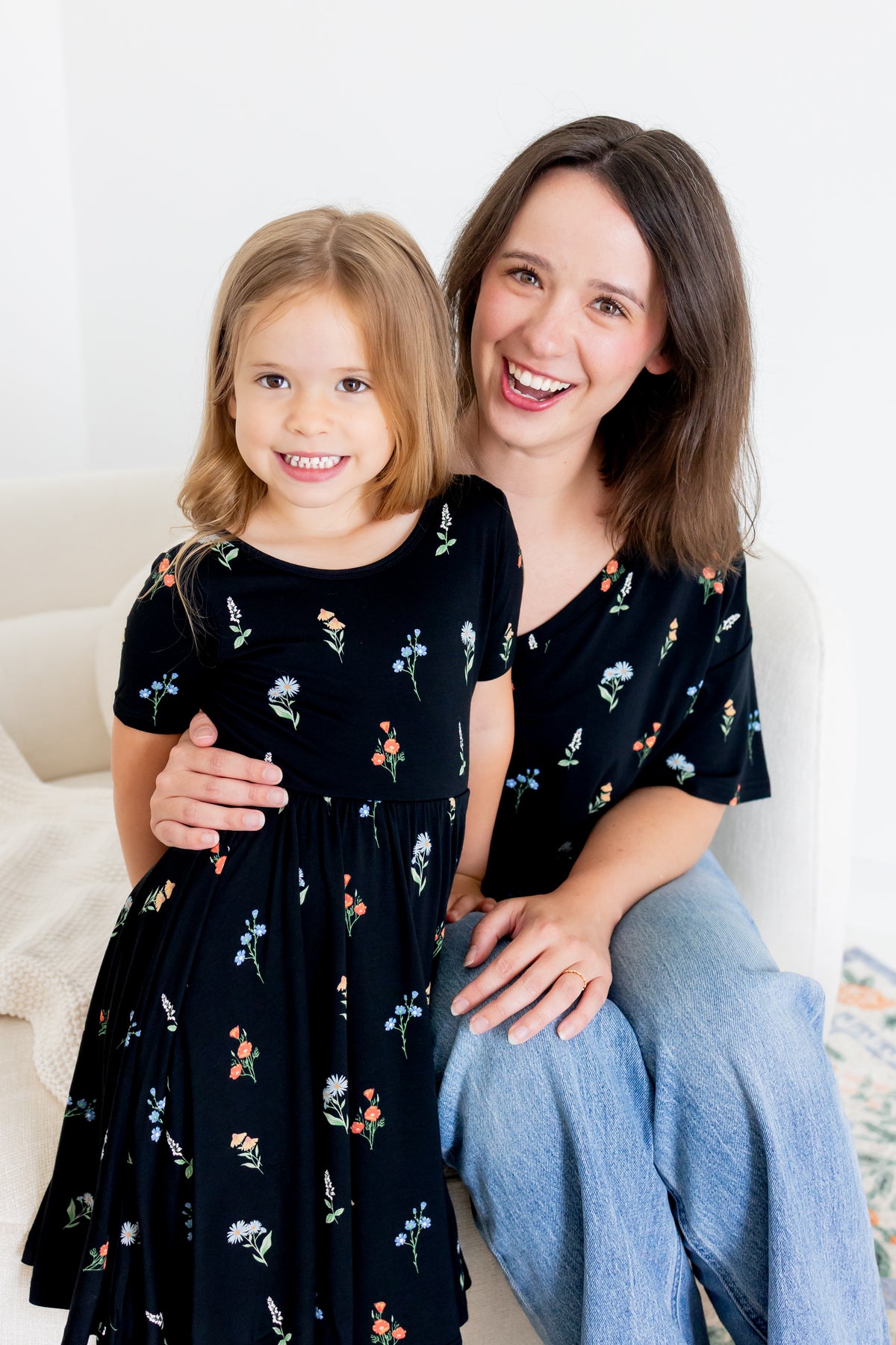 Girl standing in Twirl Dress in Midnight Wildflower print with a model wearing Women's Relaxed Fit V-Neck in similar print over blue jeans