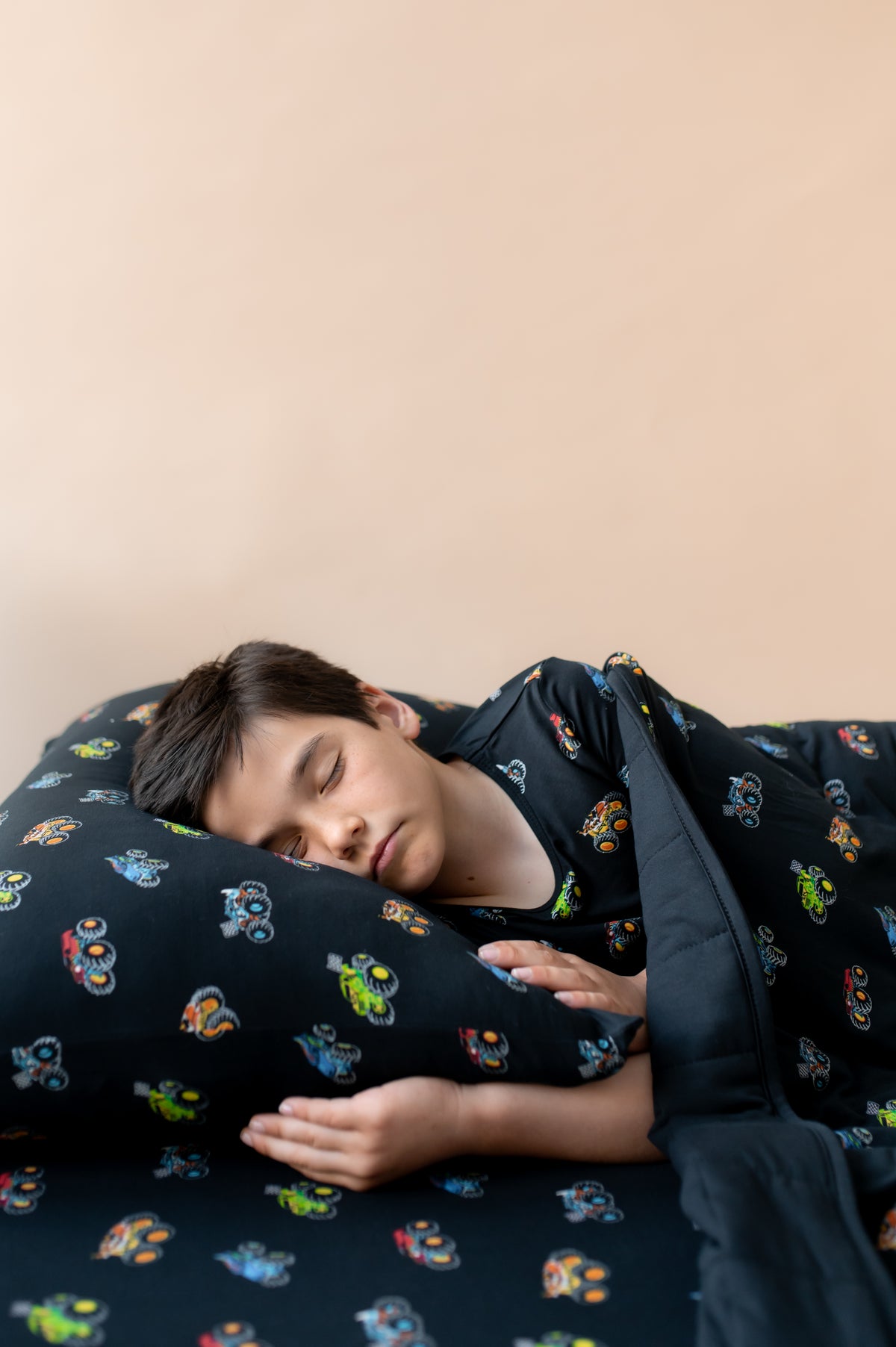 Boy sleeping on Black Standard Pillowcase and sheet in Monster Truck print covered under similar print Blanket