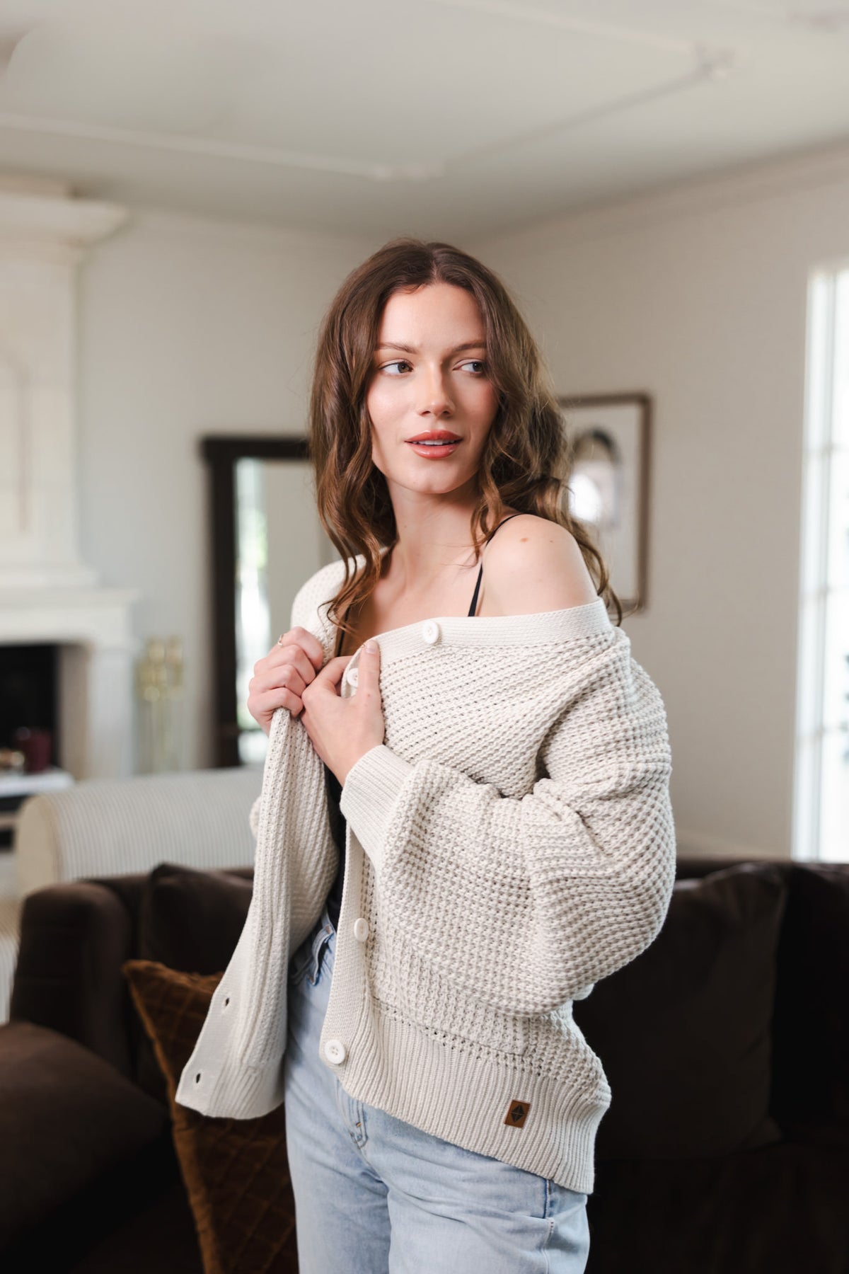 Modal wearing Chunky Knit Women's Waffle Cardigan in Oat over a blue jeans standing in a living room