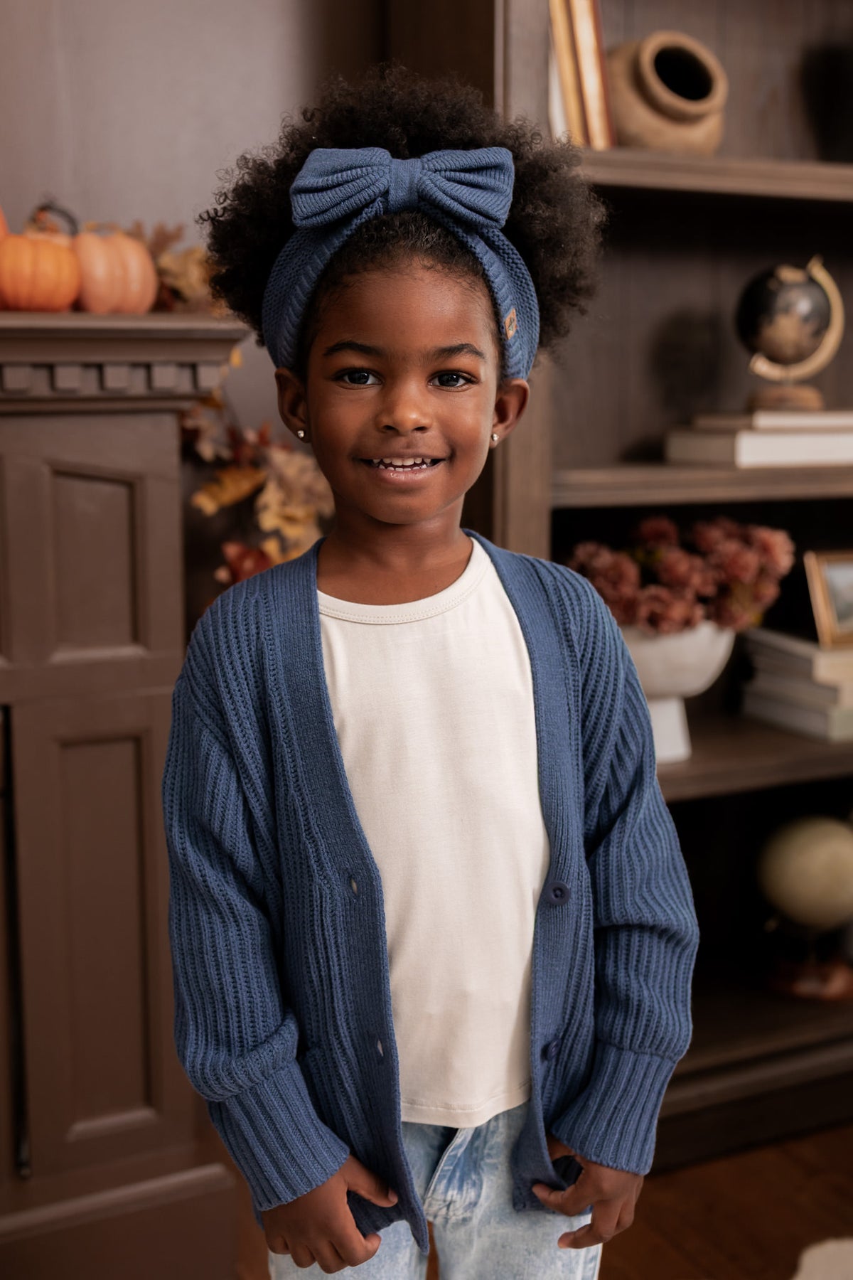 Modal standing in a living room wearing Chunky Knit Bow Headband in Oxford over white T-shirt and Chunky knit oversized cardigan in Oxford