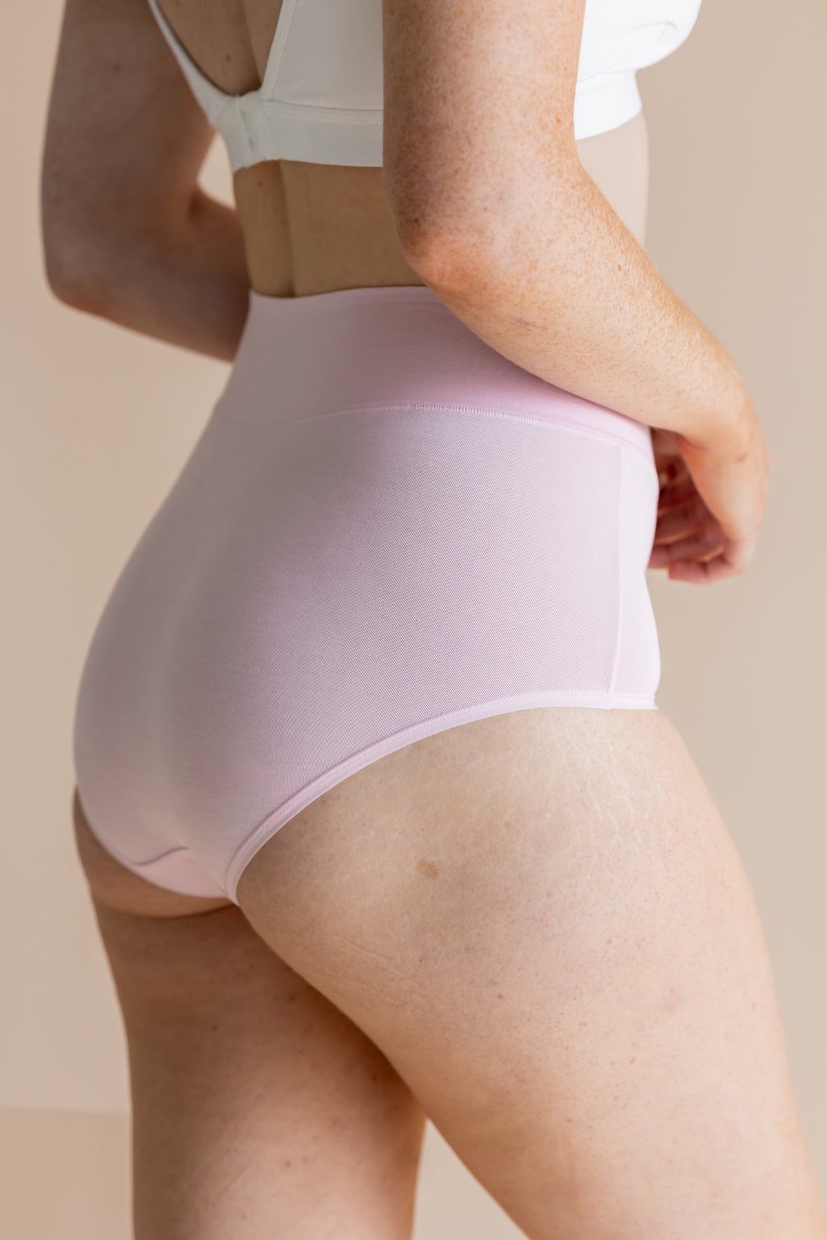 Person wearing light purple high-waisted underwear on a beige background
