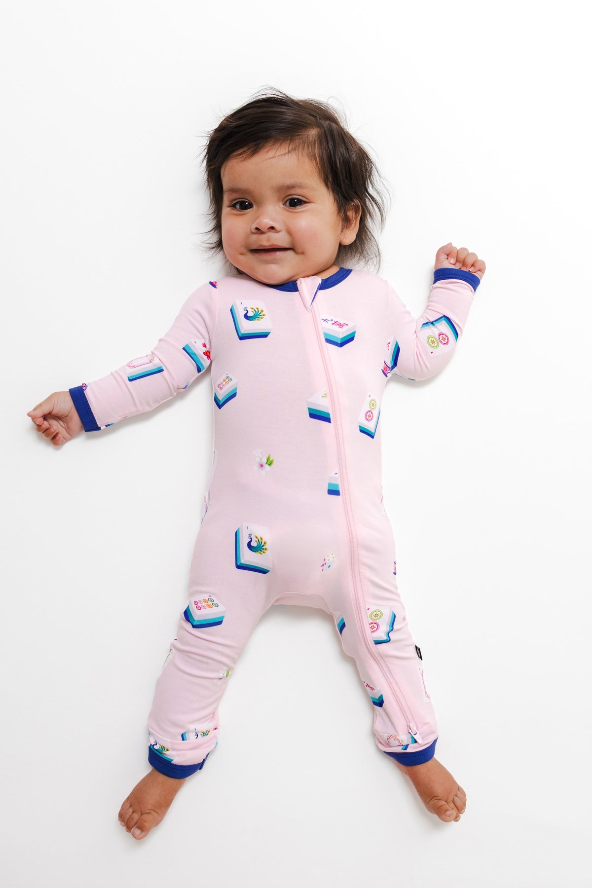 Baby wearing Zippered Romper in Sakura Mahjong print on a white background