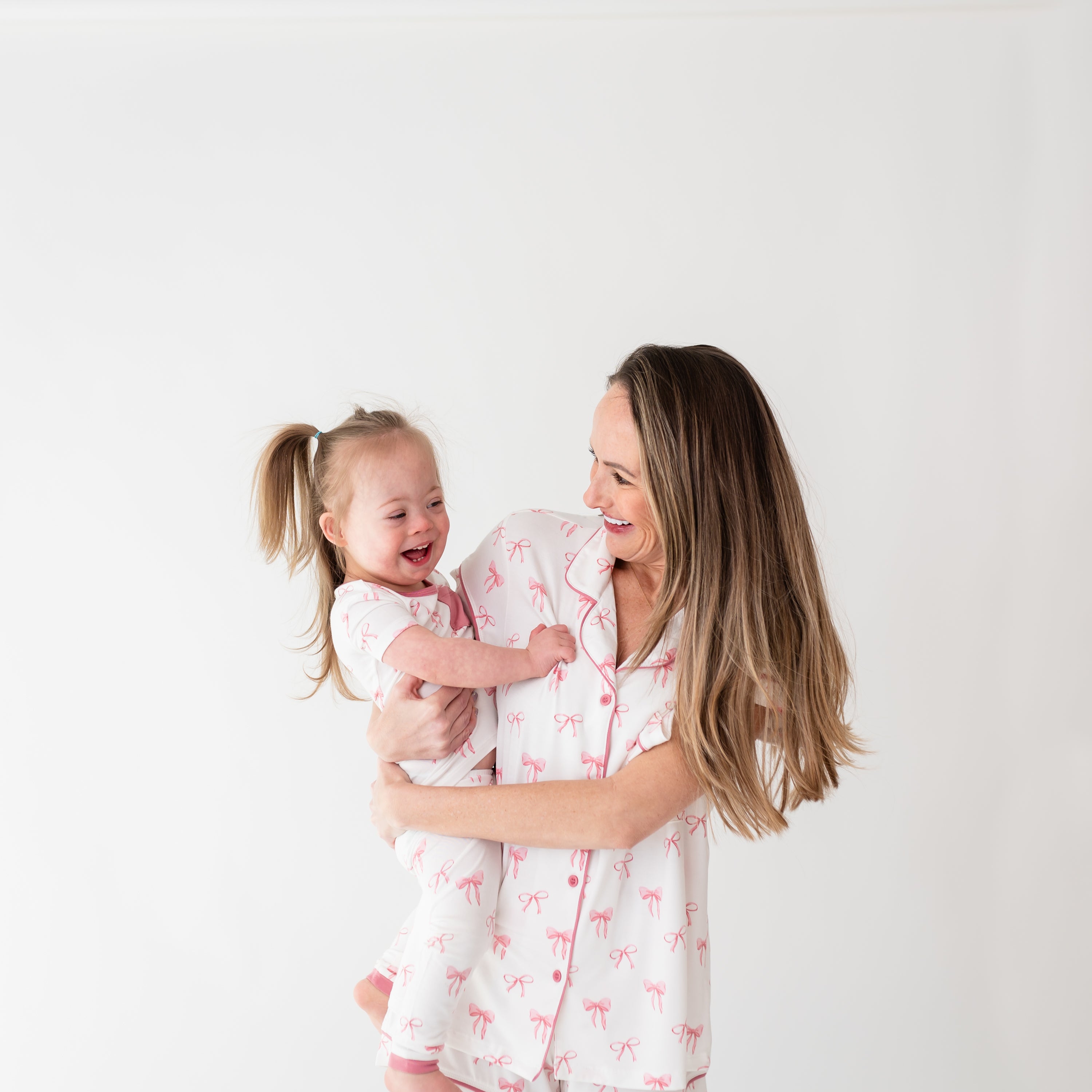 A mom modeling Women’s Short Sleeve Pajama Set in Bow while holding daughter with matching pajamas close up