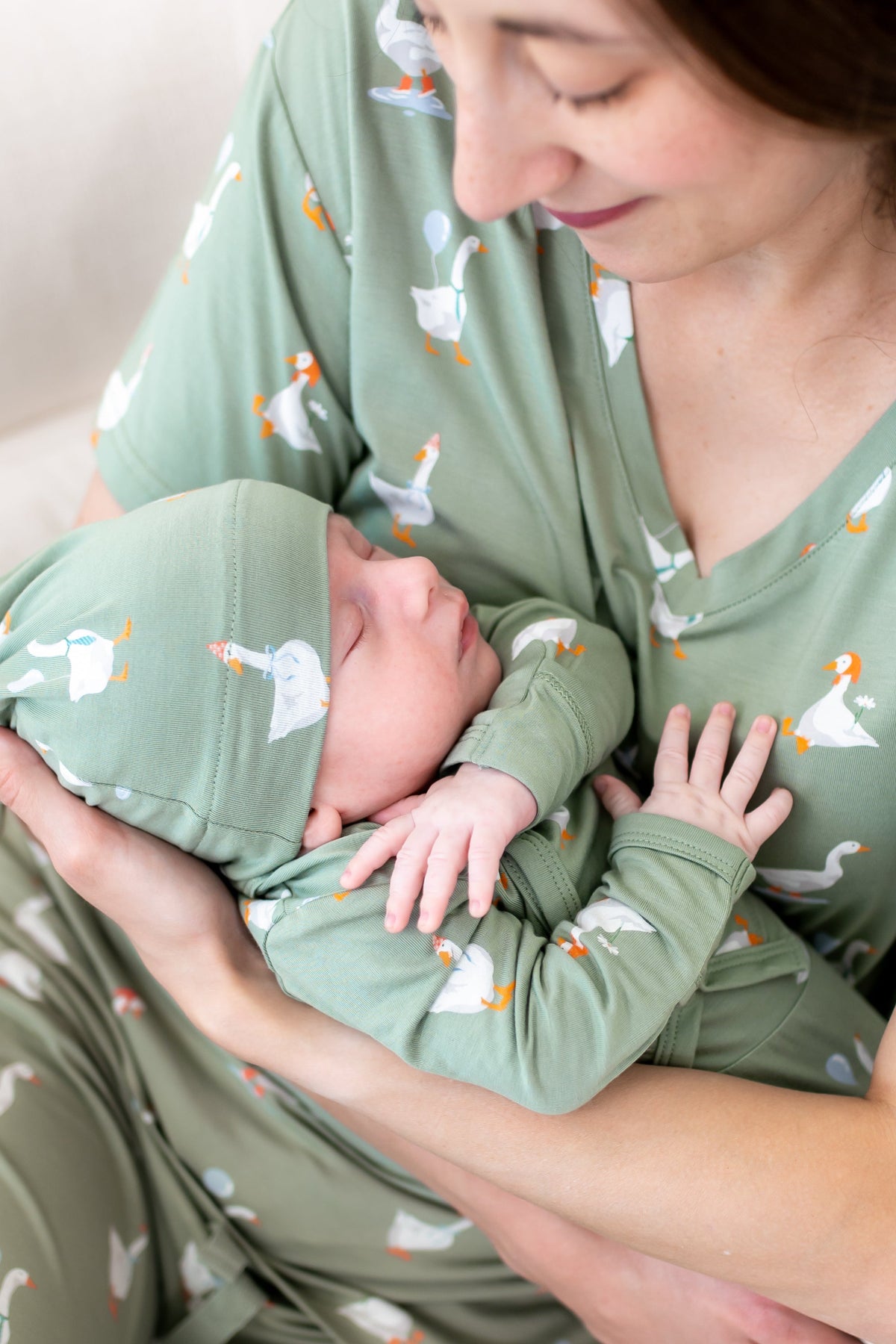 Close up of mother holding sleeping newborn wearing the Take Me Home Set in Silly Goose