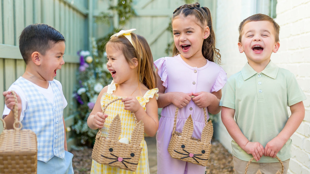 Four children standing outdoors, each holding a small easter basket with a bunny design.