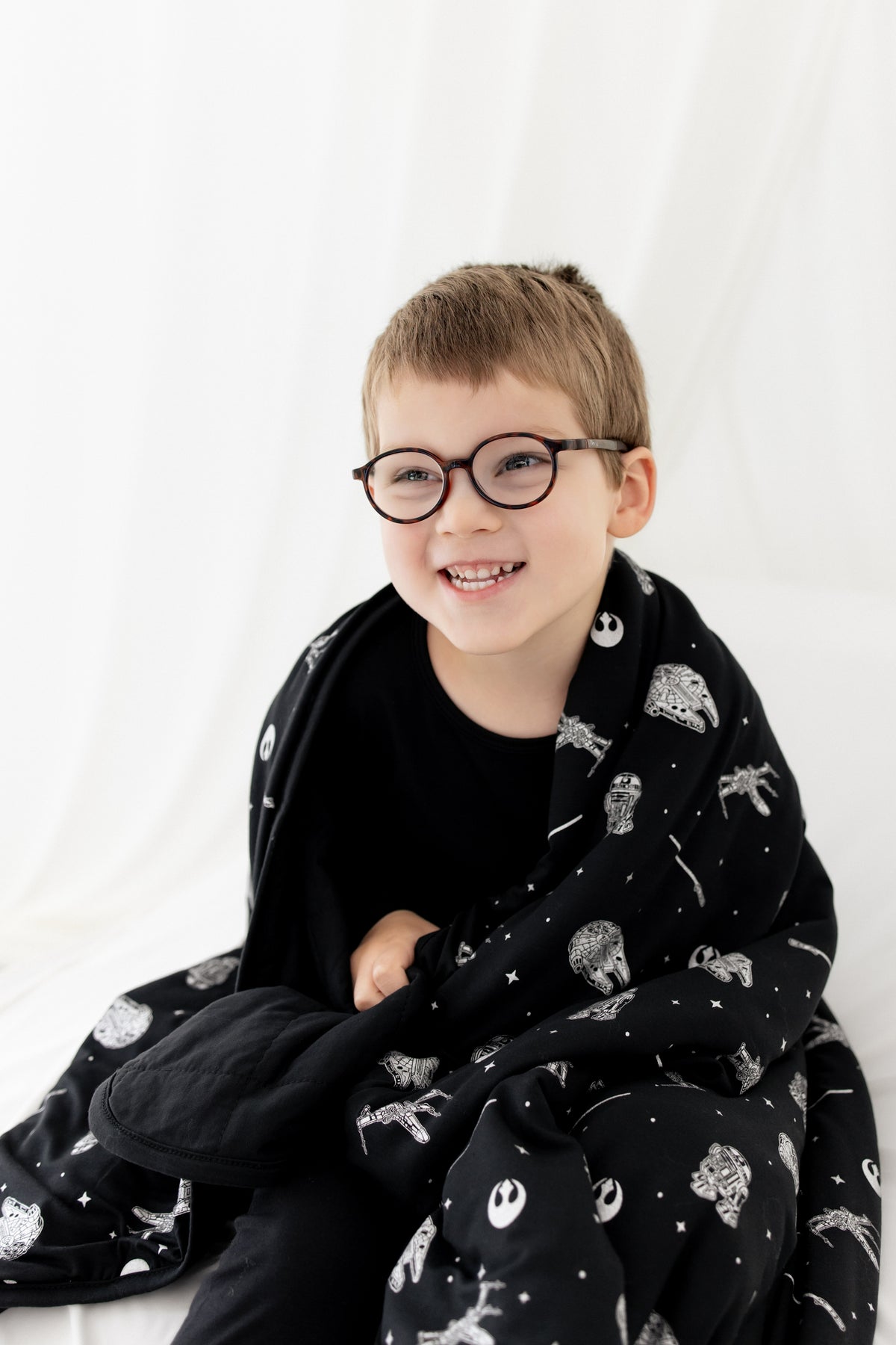 Close up of a young boy with the Toddler Blanket in STAR WARS™ 1.0 wrapped around his shoulders