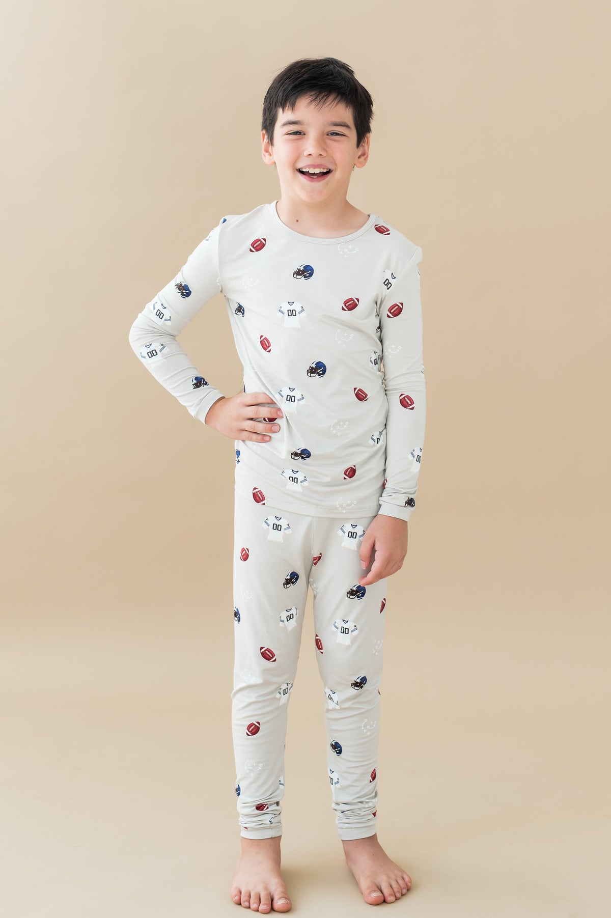 Boy wearing Long Sleeve Pajamas in Vintage Football print on a beige background