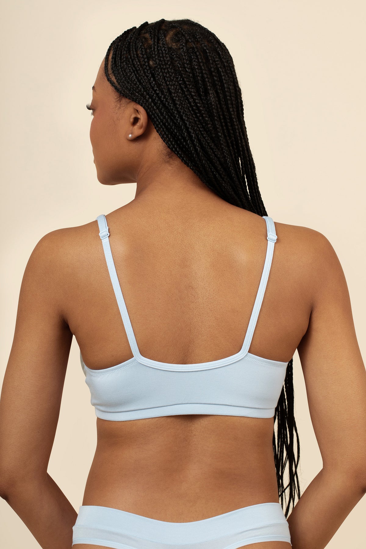Woman wearing a light blue bra set on a beige background