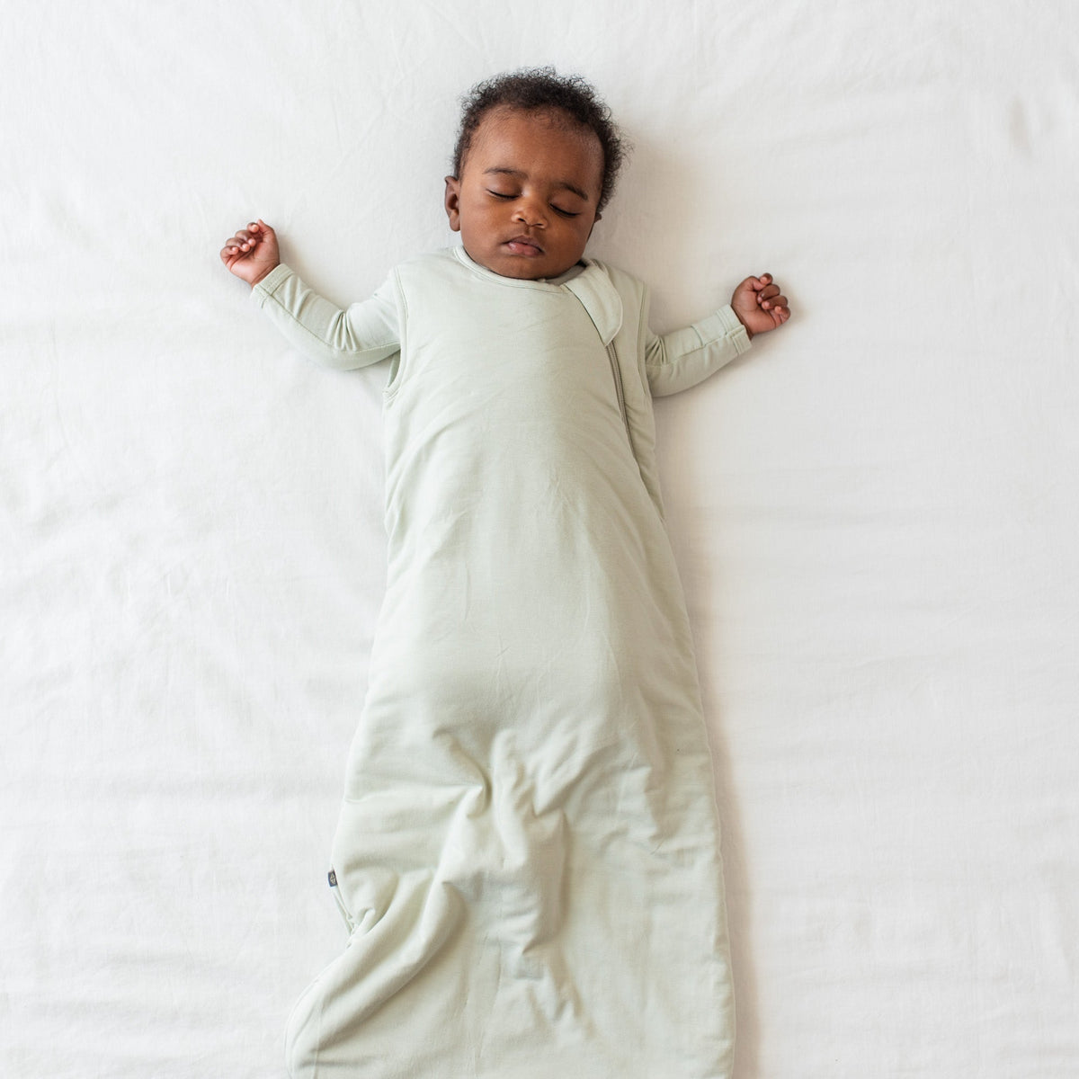 Baby sleeping in sage green sleep bag