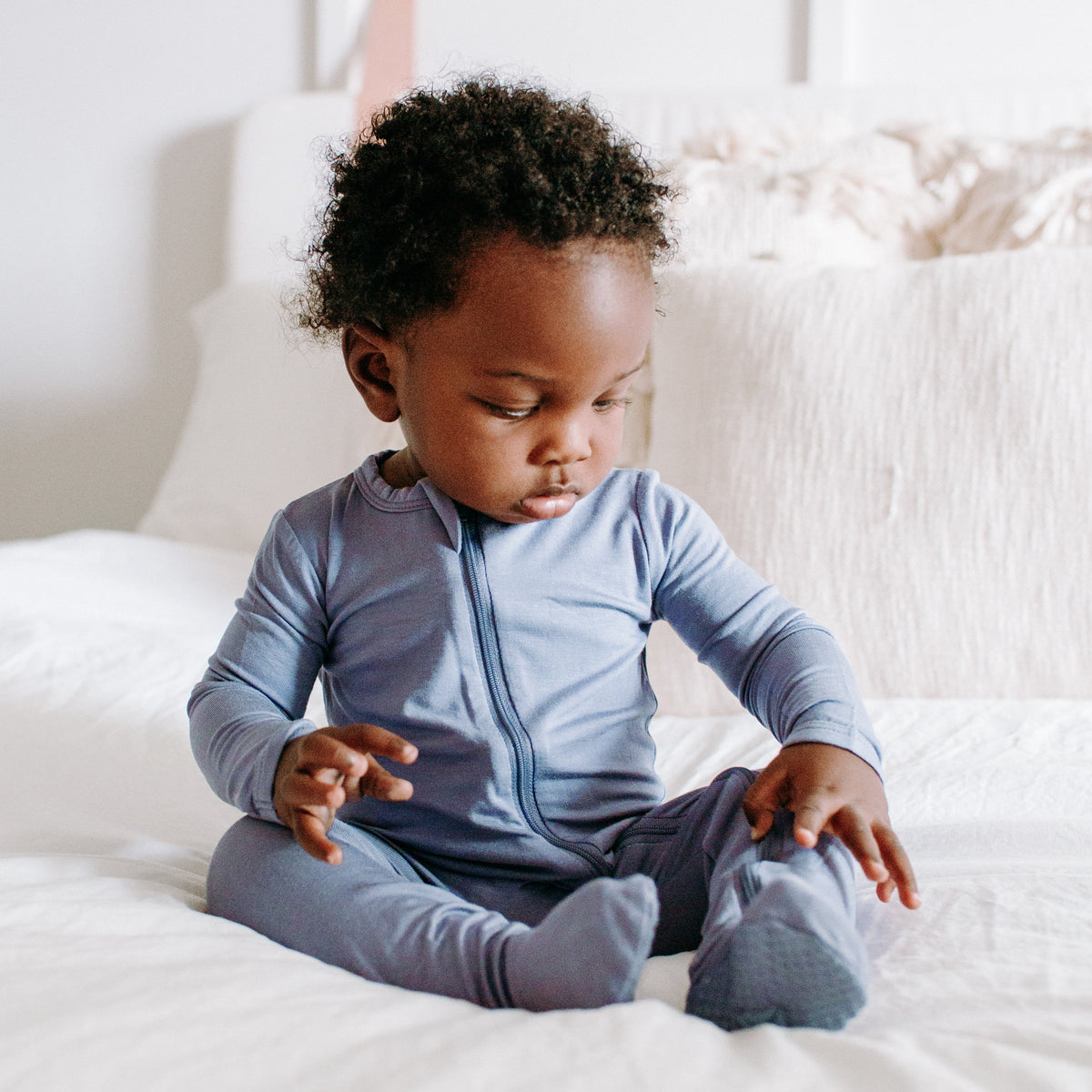 baby sitting up in a kyte zippered footie