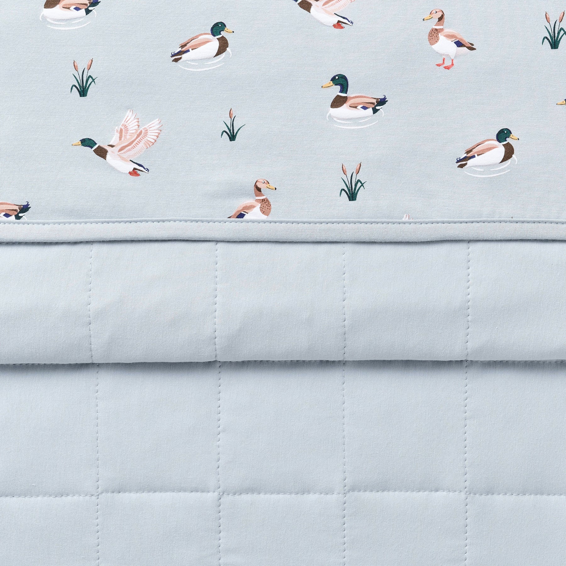 Close up of the Baby Blanket in Mallard Duck showing the quilted blue backing and patterned smooth top layer