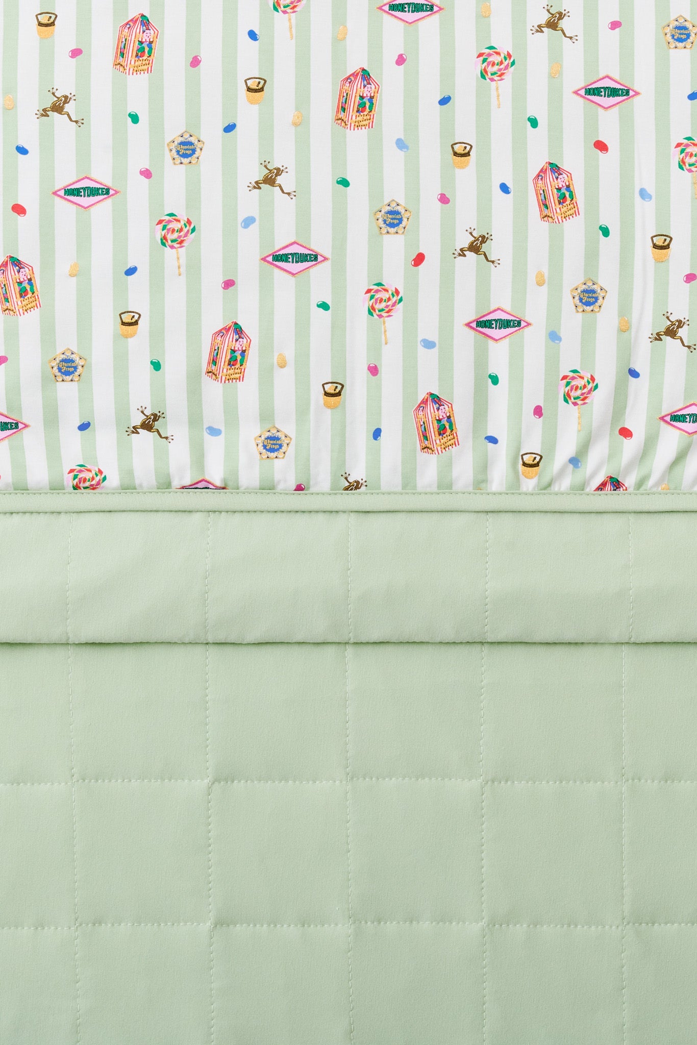 Green and white striped toddler blanket with colorful Harry Potter pattern print on it and plain green fabric at the back