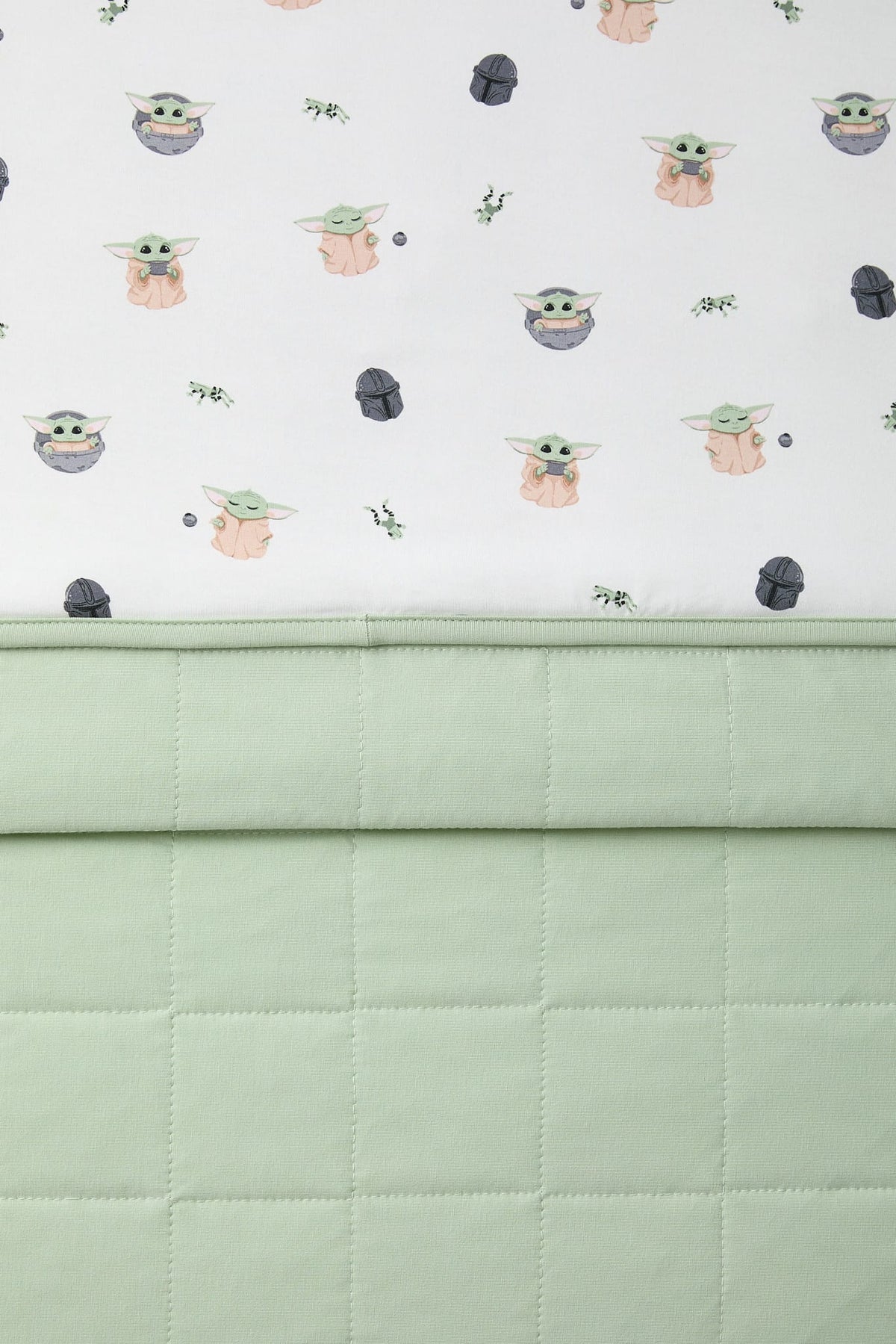 Close up of the light green quilted backing and the smooth printed top layer shown on the Toddler Blanket in Grogu™ 1.0