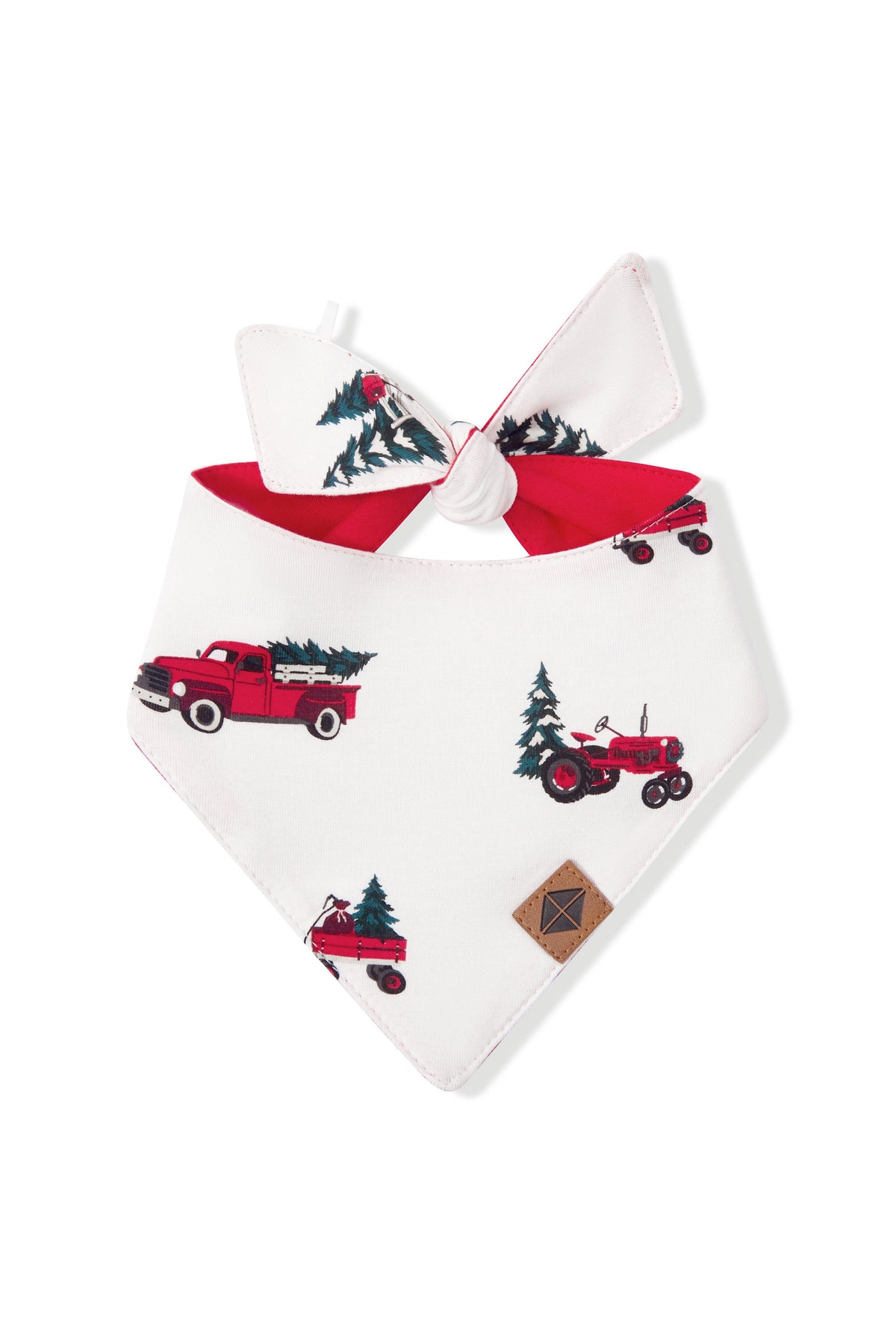 A white pet bandana with a red tie and a holiday-themed print of vintage red trucks and tractors carrying Christmas trees, shown on a plain white background.