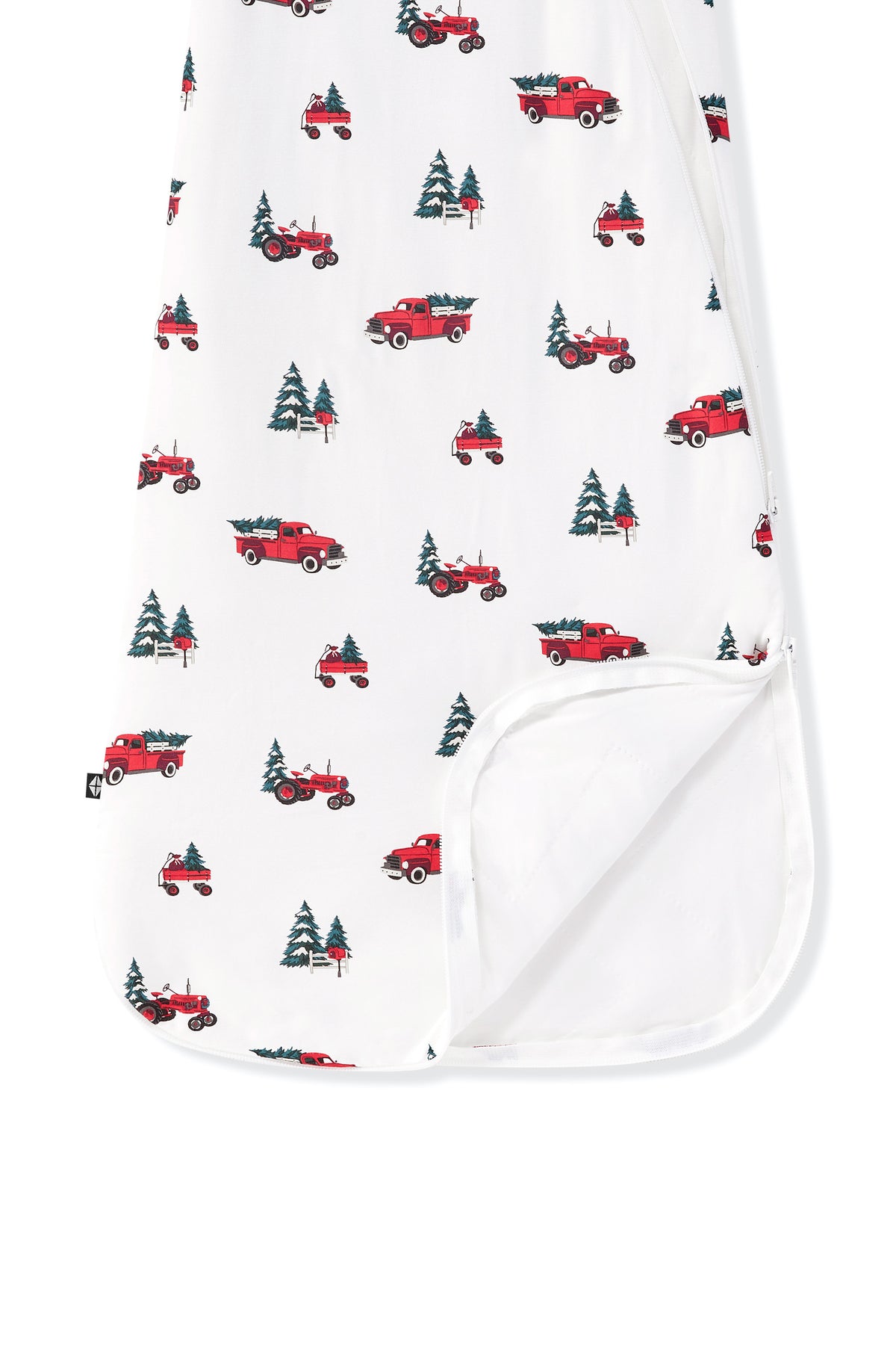 A close-up of a white baby blanket or swaddle with a repeating pattern of red pickup trucks carrying Christmas trees, with a folded-over corner showing a solid white reverse side.