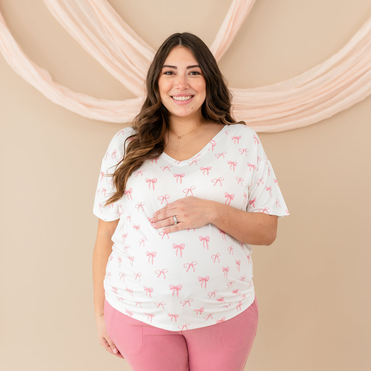 Pregnant woman smiling and wearing Women’s Relaxed Fit V-Neck in Bow with Apple Blossom Ribbed Jogger Pants. 