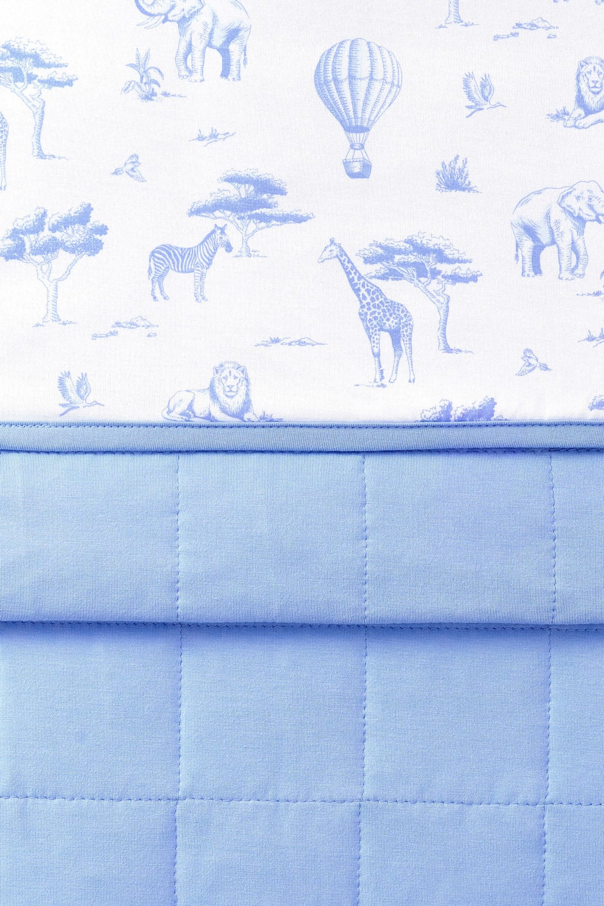 Close up of the Youth Blanket in Toile Safari 1.0 showing the quilted blue backing and smooth printed top layer