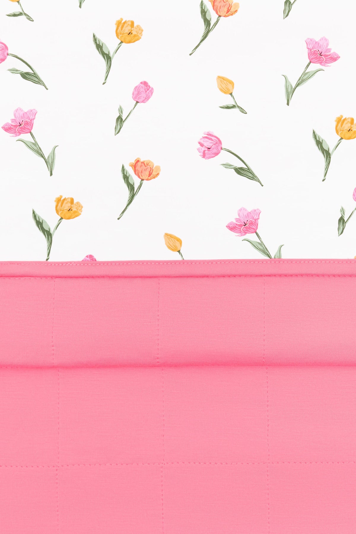 Close up of the Youth Blanket in Tulip 1.0 showing the quilted pink backing and floral smooth top layer