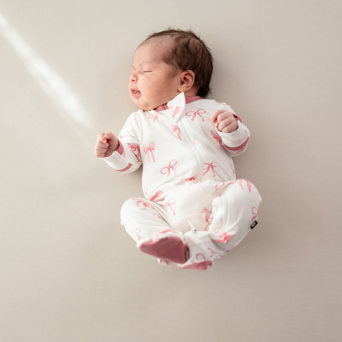 Baby wearing Zippered Footie newborn pajamas in Bow 