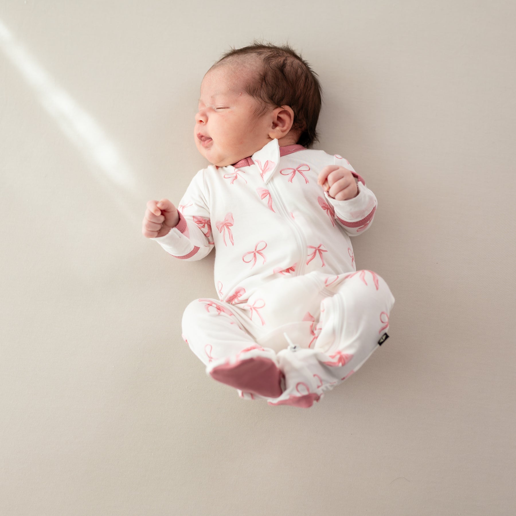 Baby wearing Zippered Footie newborn pajamas in Bow 