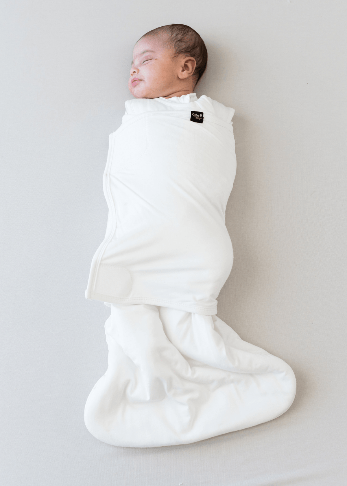 Baby sleeping wearing kyte baby sleep bag swaddler in cloud