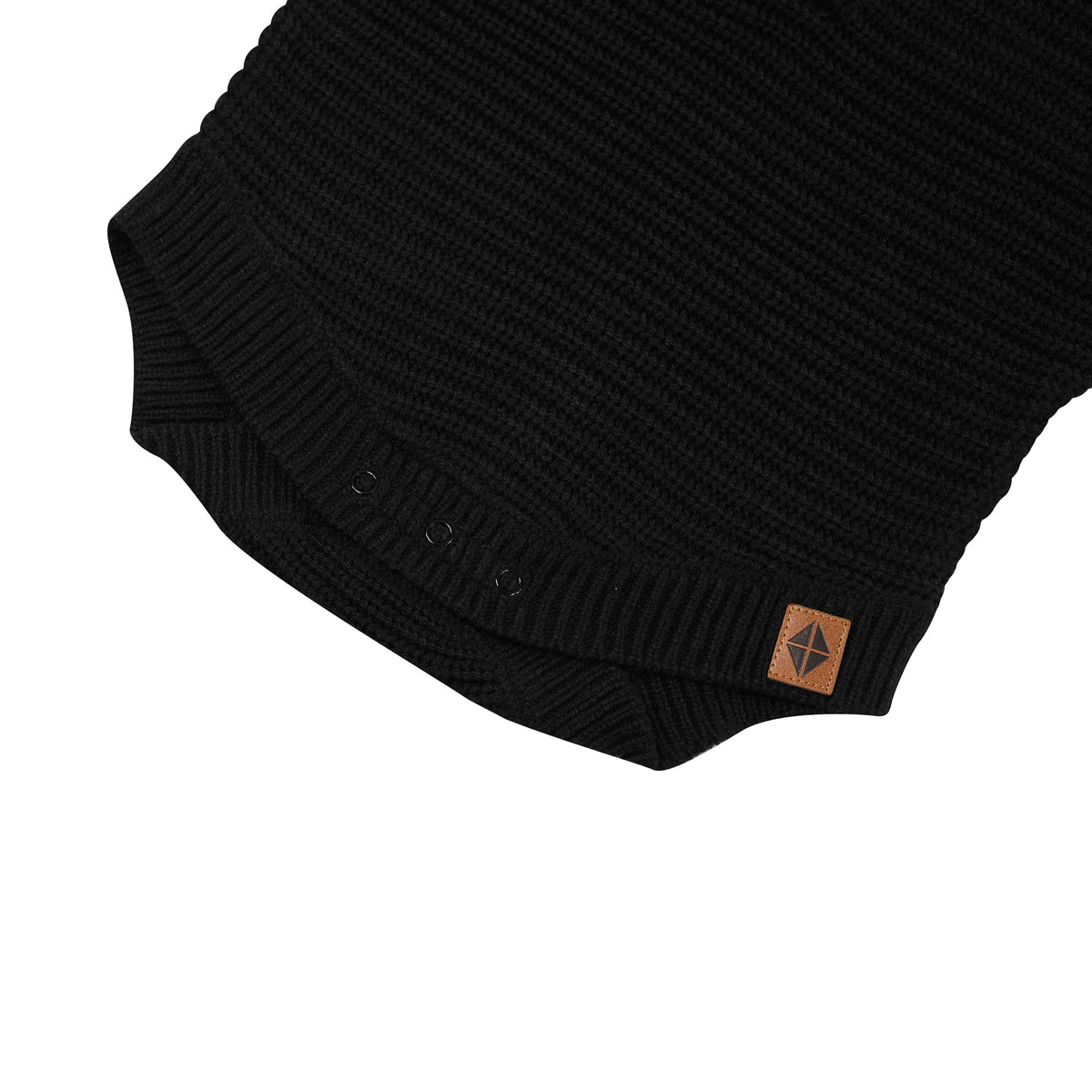 Snap closures shown on the Chunky Knit Romper in Midnight with the Kyte Baby vegan leather tag visible