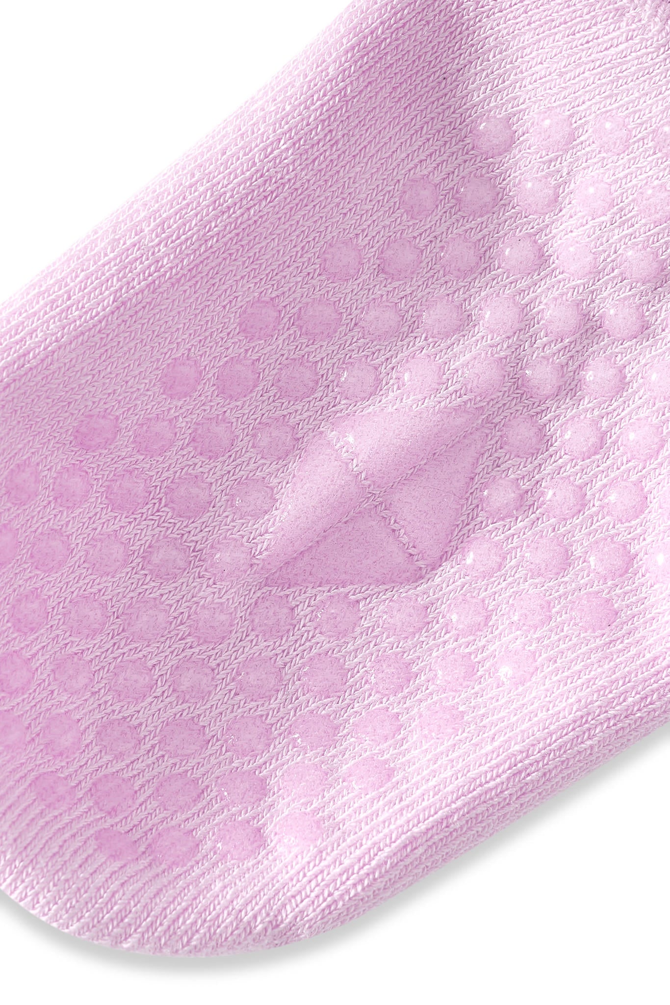 A close-up of a light pink knit sock with raised circular grip dots on the sole, shown against a plain white background.