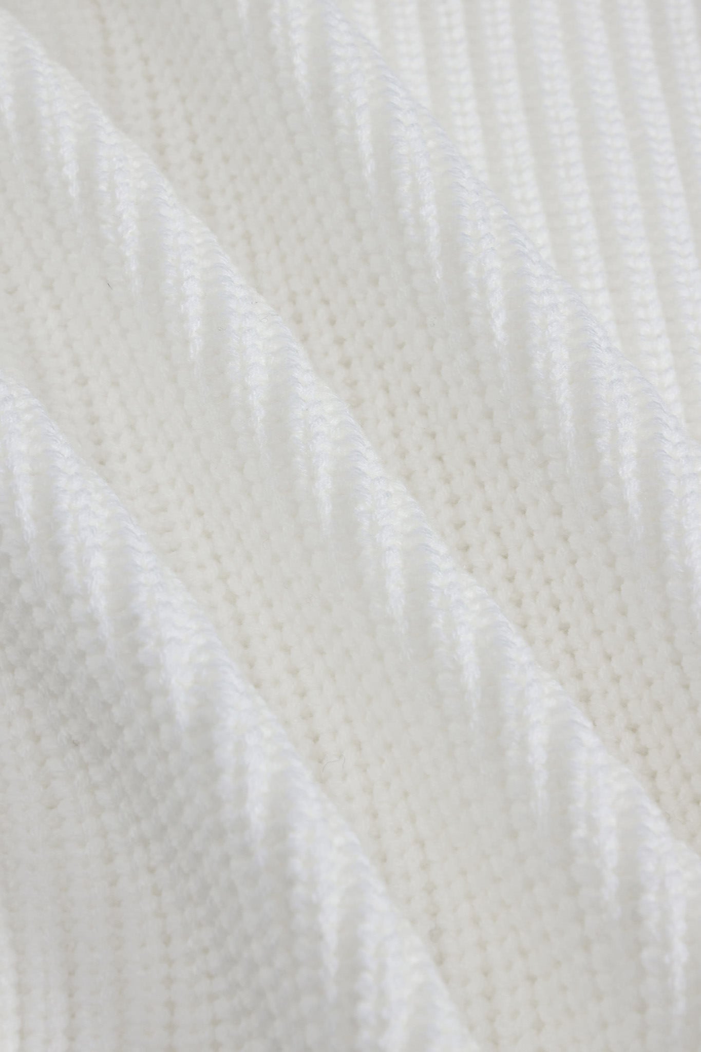 A close-up of a white textured knit fabric with a subtle diagonal ribbed pattern.