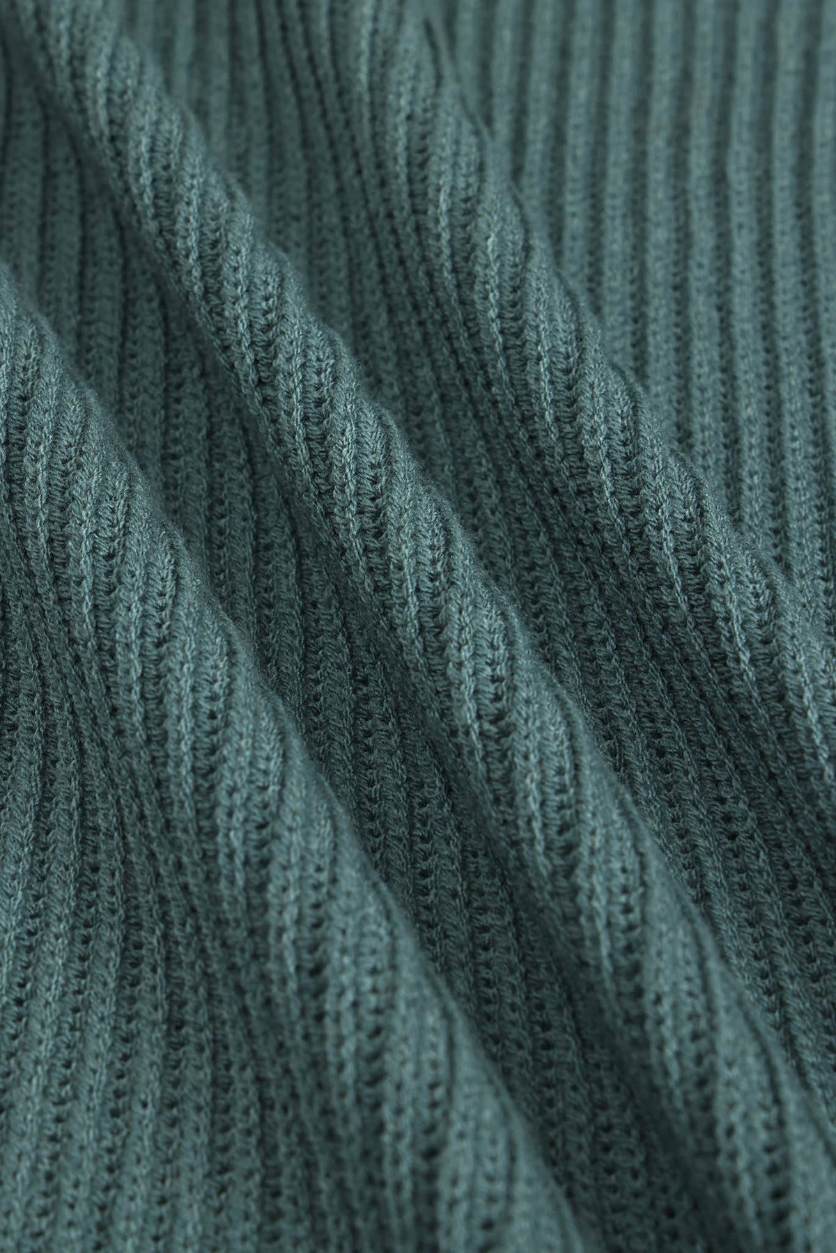 Close-up of a ribbed knit fabric in a muted blue-green color, showing the detailed texture and folds of the material.