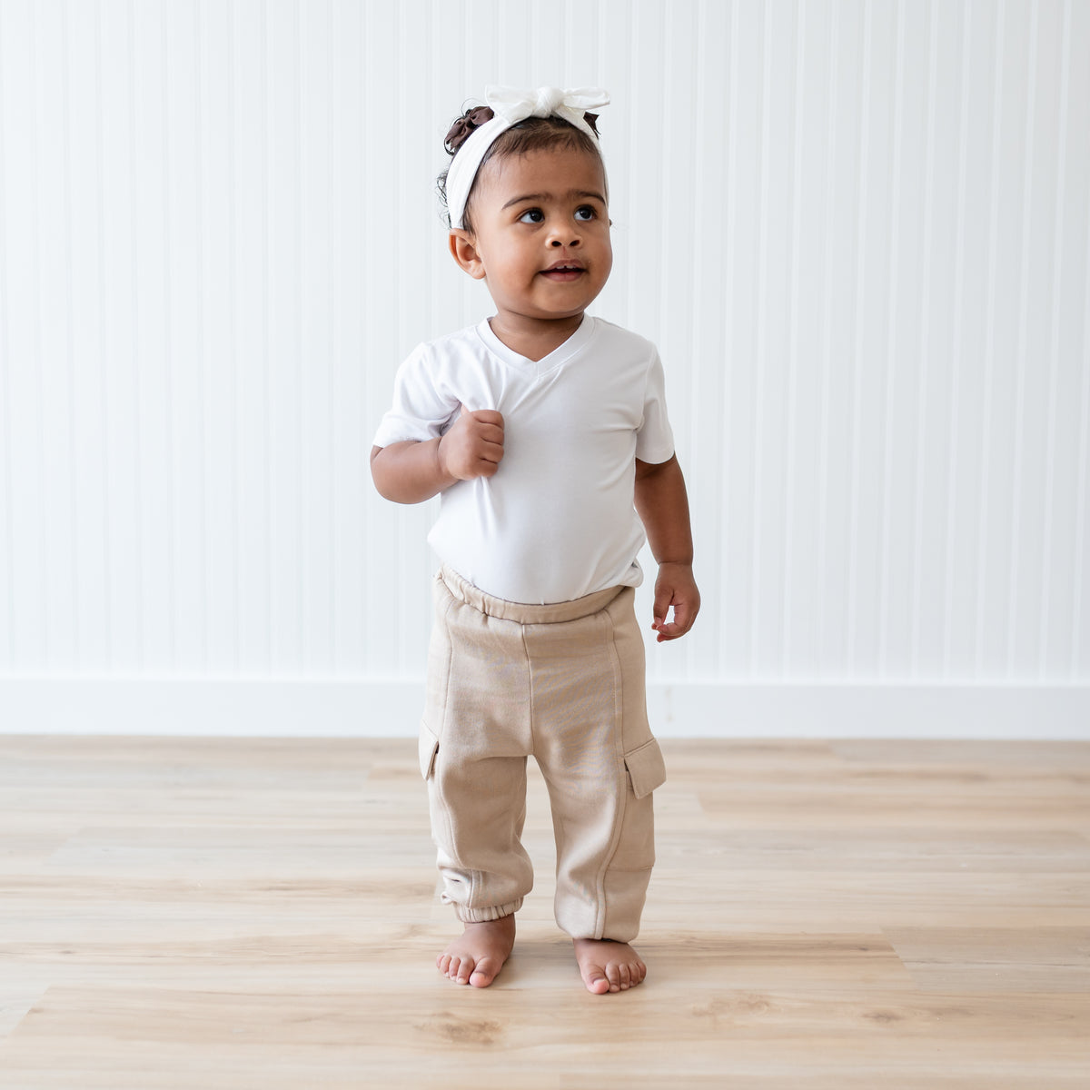 Young toddler walking wearing the Fleece Cargo Pants in Almond paired with a Snow Toddler V-Neck