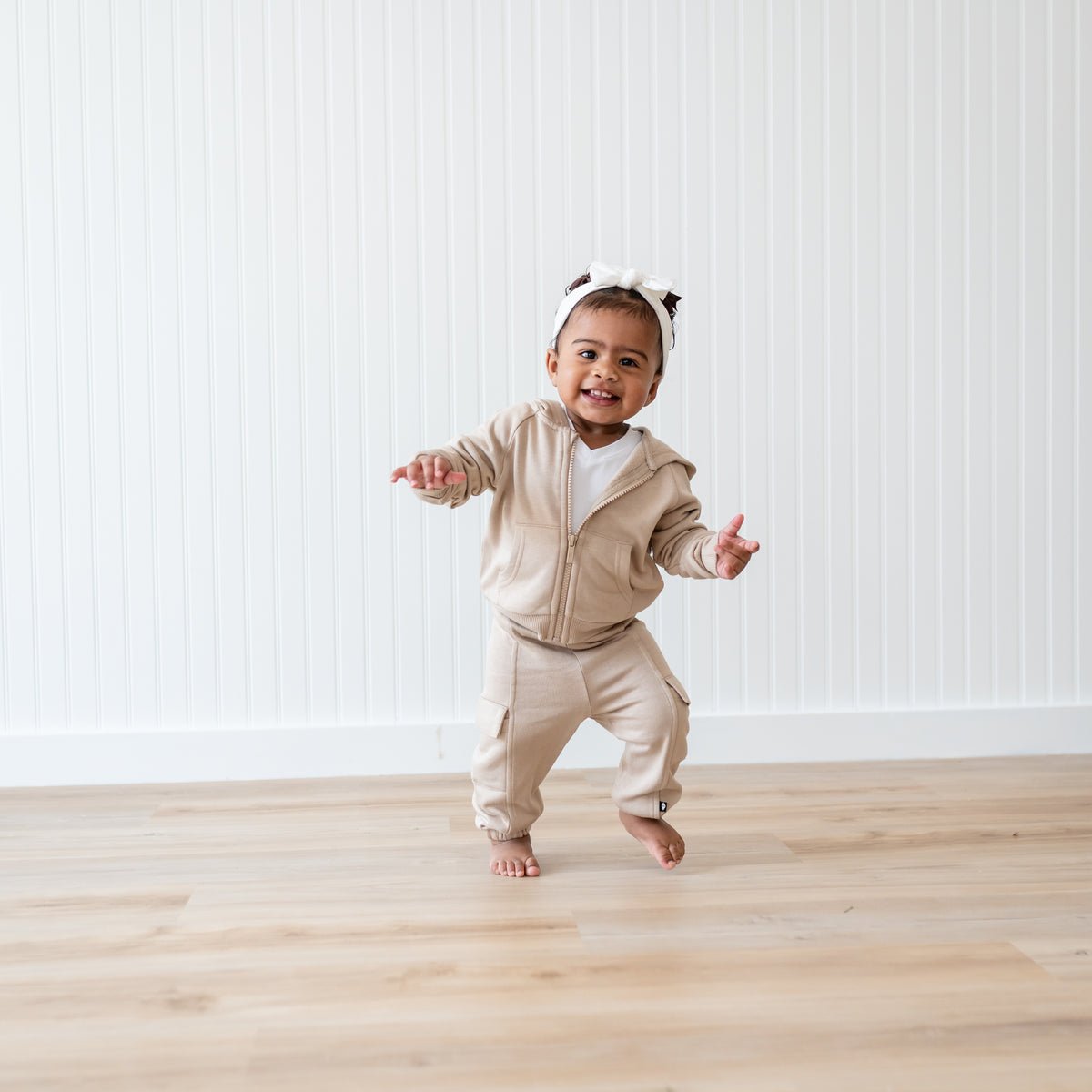 Young toddler walking wearing the Fleece Zip Up Hoodie in Almond and matching fleece cargo pants