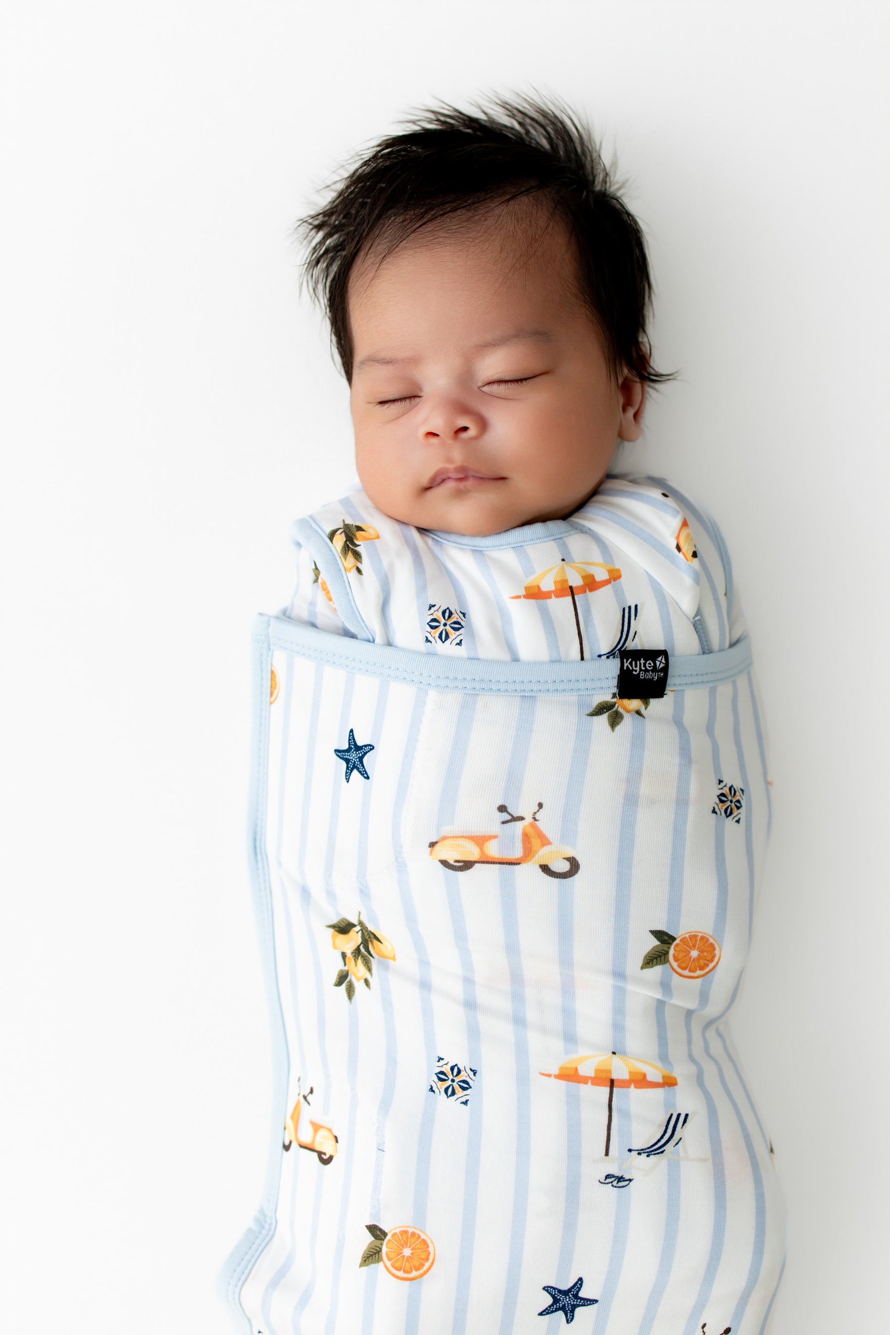 Close up of sleeping newborn swaddled in the Sleep Bag Swaddler in Amalfi Coast 1.0 on white background